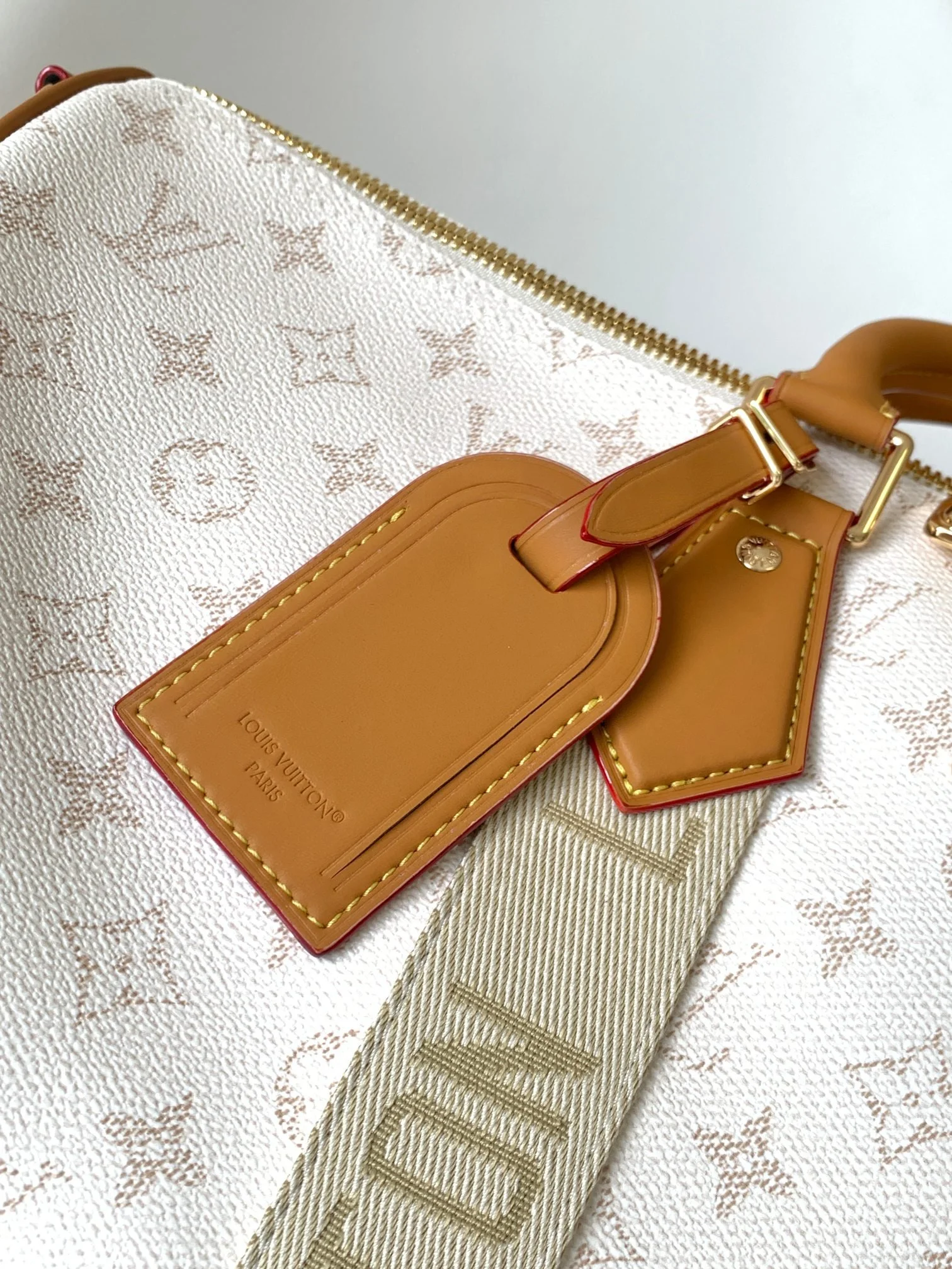 Close-up of a Louis Vuitton handbag with tags, resting on a patterned bag with gold zipper.