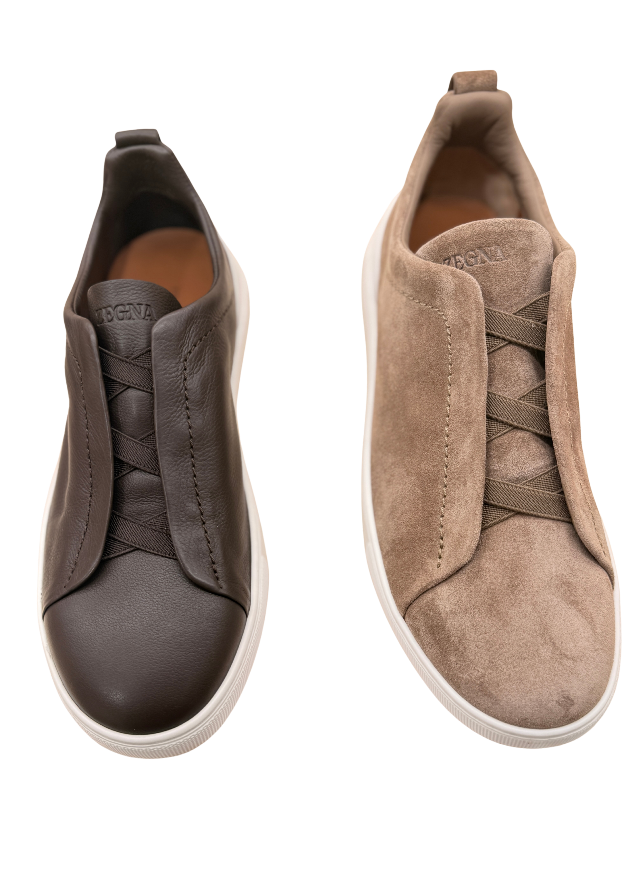 Pair of men's sneakers, one in dark brown leather and the other in light brown suede, with white soles, viewed from above.
