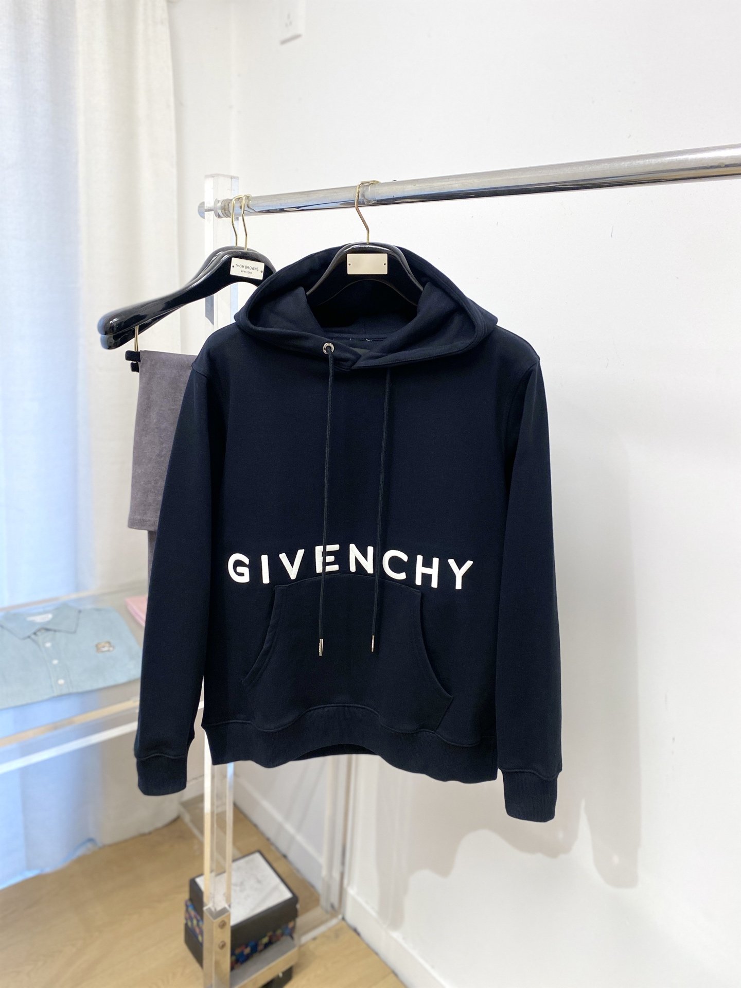 Black hoodie with the brand name 'Givenchy' printed across the front, hanging on a clothing rack.