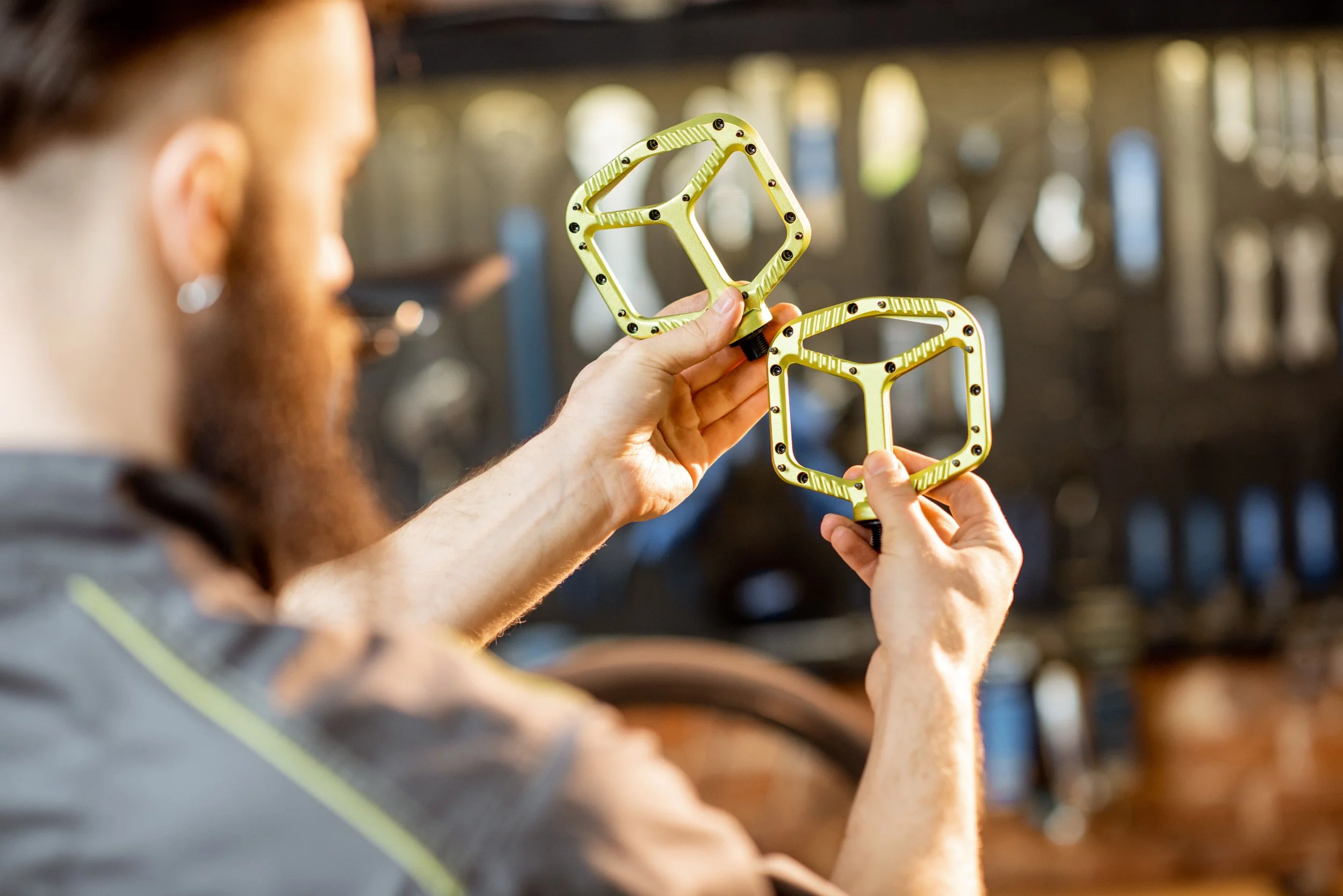 A person holding a pair of yellow bicycle pedals.