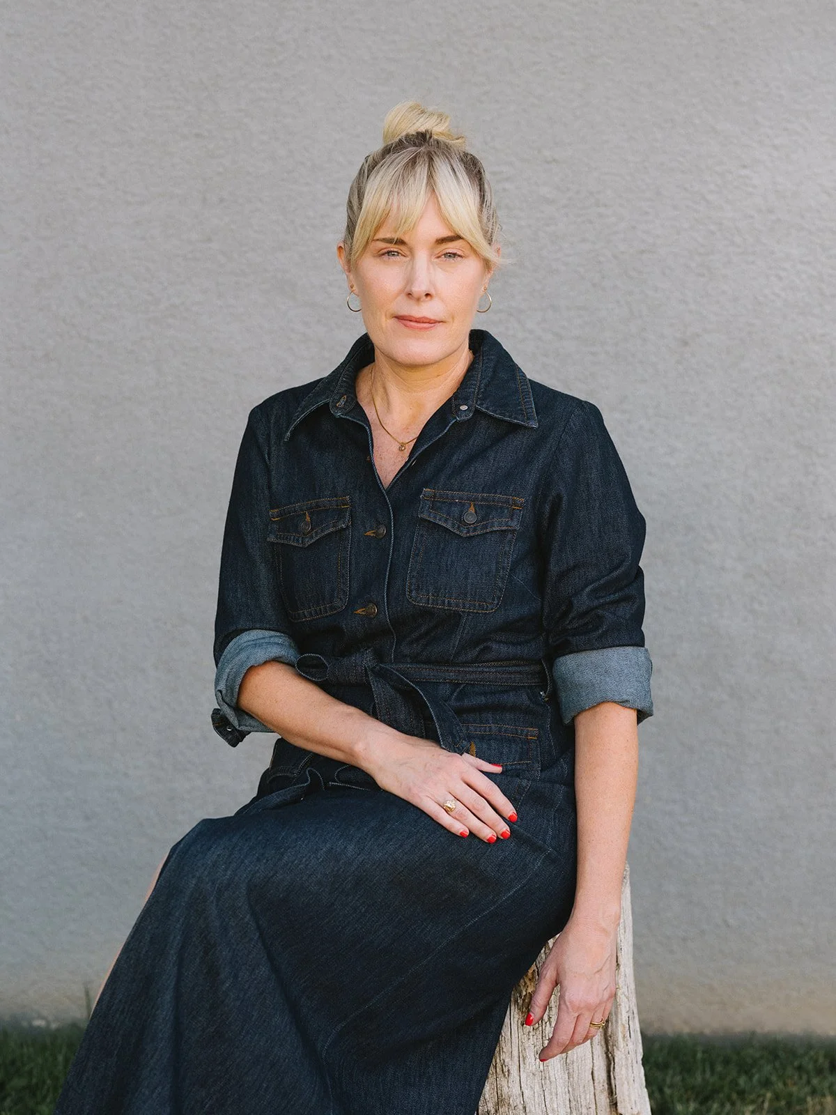 Jenny Walters, LMFT, licensed depth psychotherapist in Los Angeles, seated in a denim dress against a grey wall