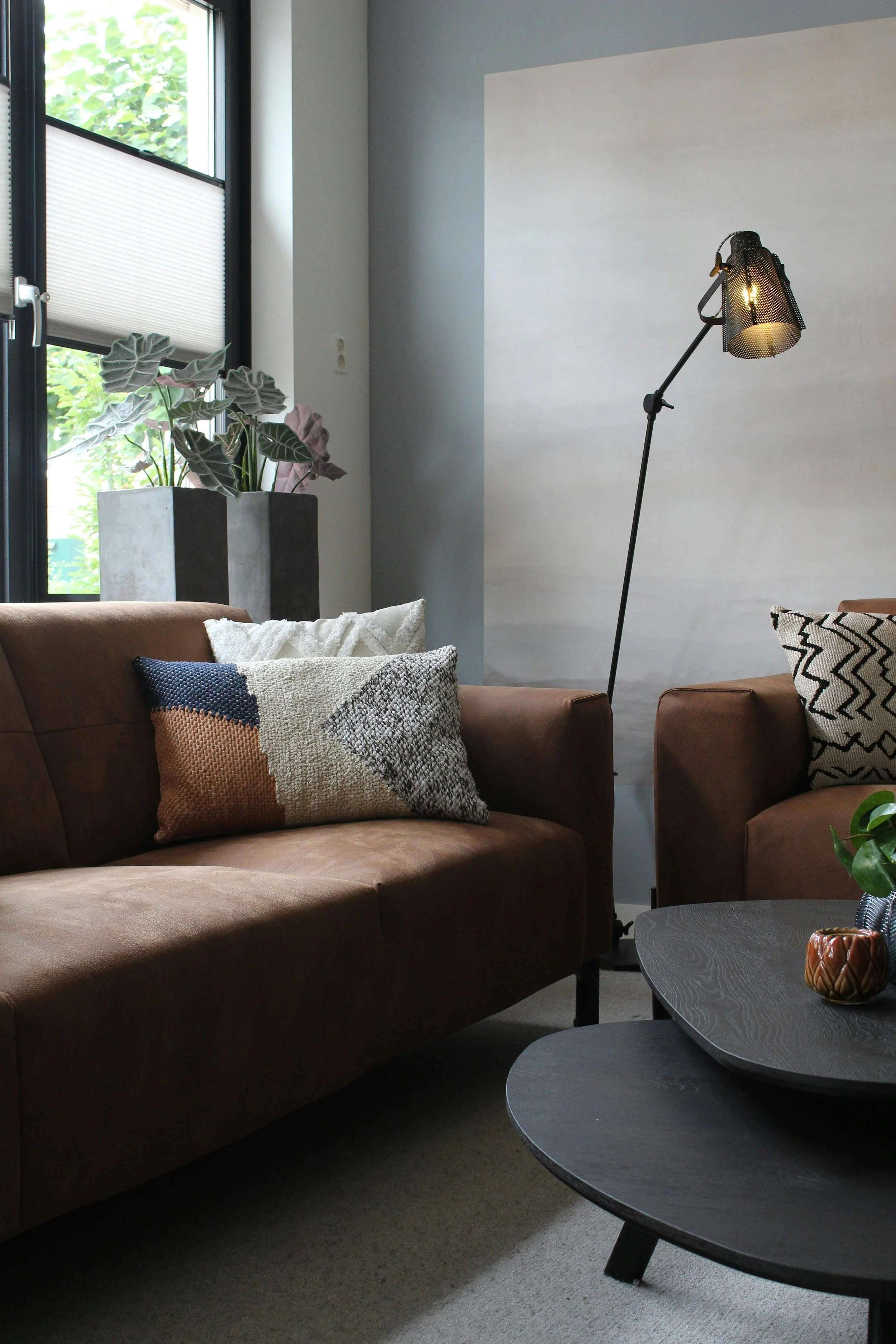 A warm therapy office interior with a brown leather sofa, textured pillows, floor lamp, and potted plants — in-person therapy space at Jenny Walters Psychotherapy in Highland Park, Los Angeles