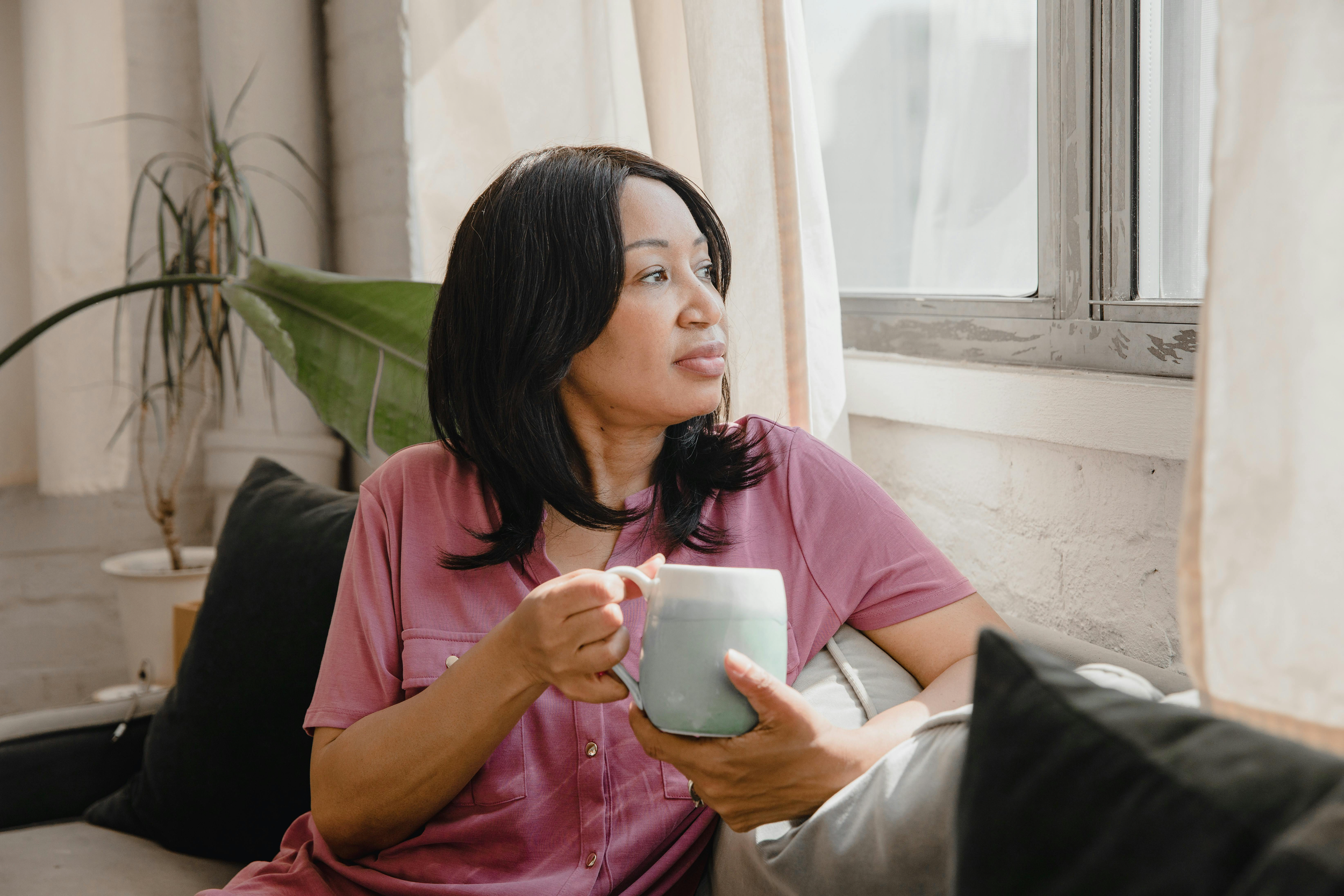 A client sitting on the couch and looking out the window in a reflective state.