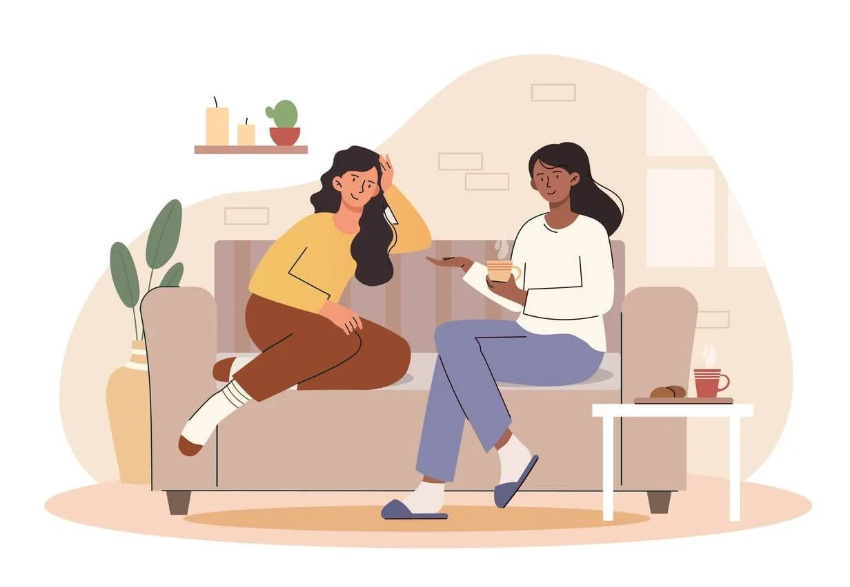 Two women sitting together and talking on the couch.
