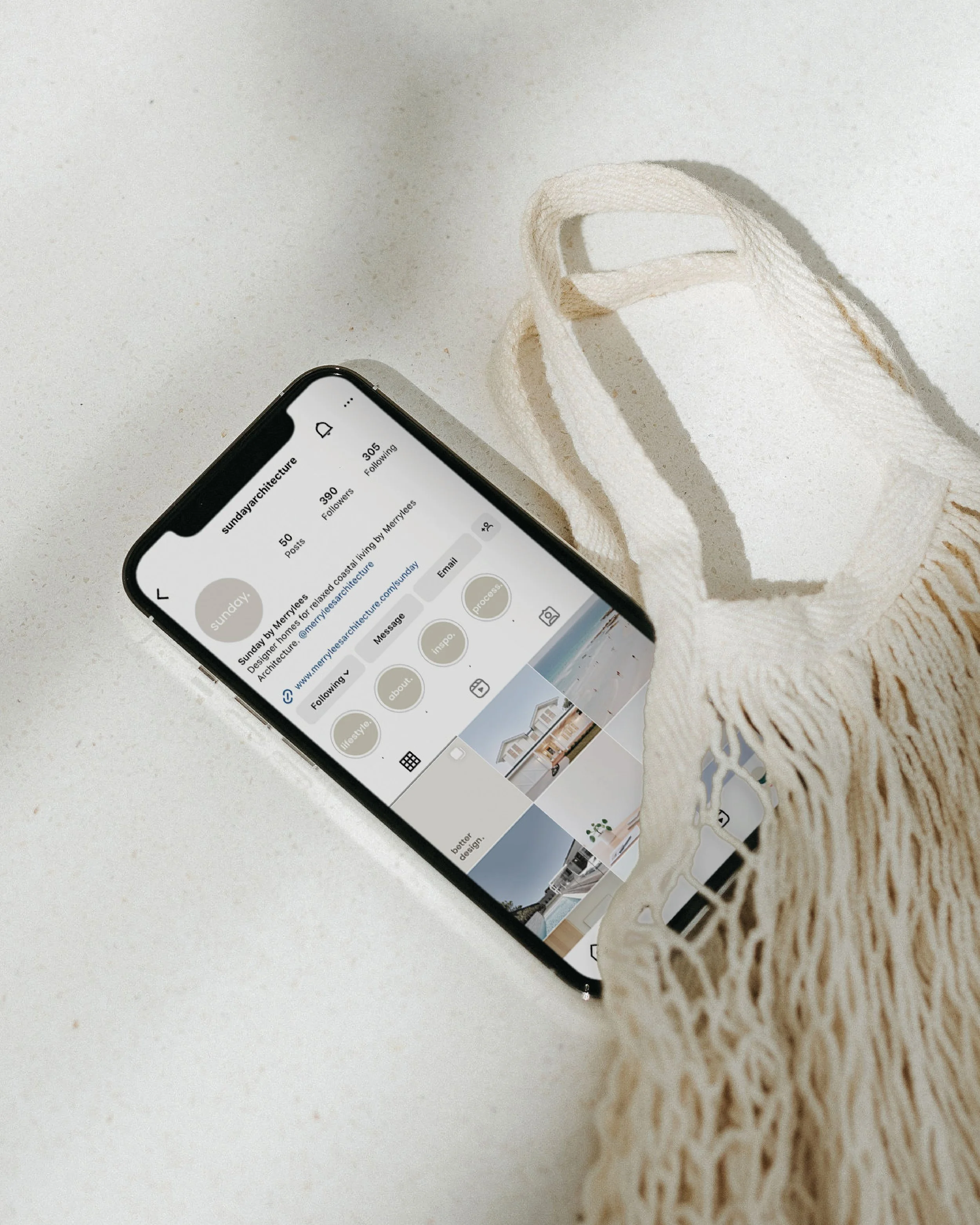 Smartphone displaying an Instagram profile on a light surface partially covered by a woven bag.