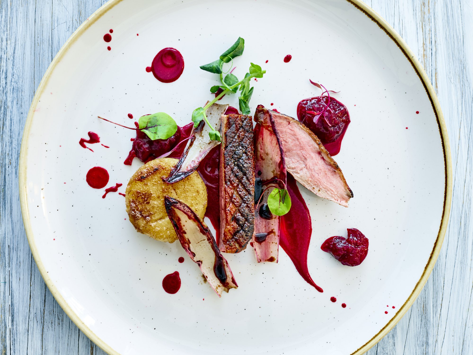 Refined plated dish with seared meat, roasted vegetables, and vibrant sauce, showcasing seasonal, ingredient-driven cooking.