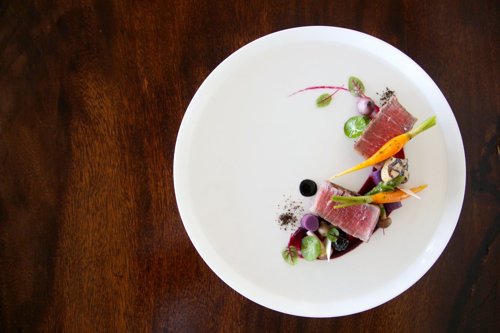 Refined tuna dish with baby vegetables and sauce, reflecting a seasonal, ingredient-driven style of cooking.
