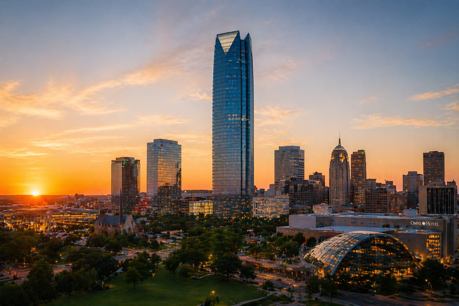 Sunset over downtown Oklahoma City, OK, with tall skyscrapers and a city park in foreground.