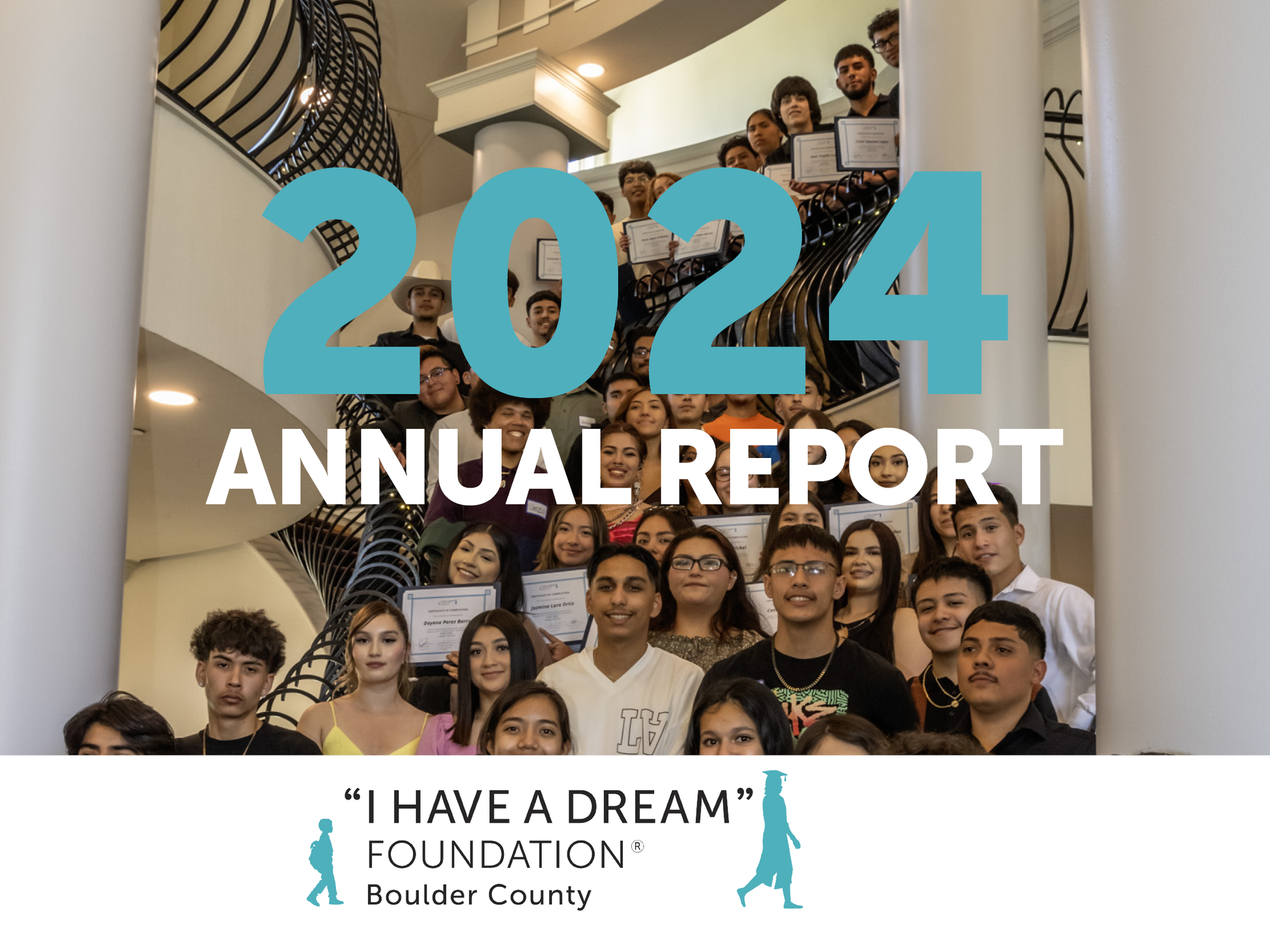 A group of diverse young people, some holding certificates, posing on a staircase inside a building with white columns and a black railing on each side, during a graduation or award ceremony. Large blue text "2024" and white text "Annual Report" overlay the image, along with a logo of a person with a cap and gown, and the text "I Have a Dream" Foundation Boulder County at the bottom.