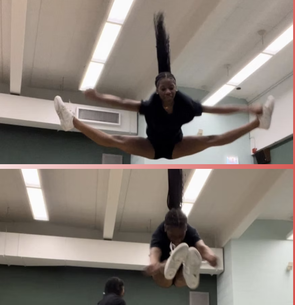 Two women performing aerial acrobatics indoors, one in a split mid-air with legs extended to the sides, the other crouching in a jumping pose.