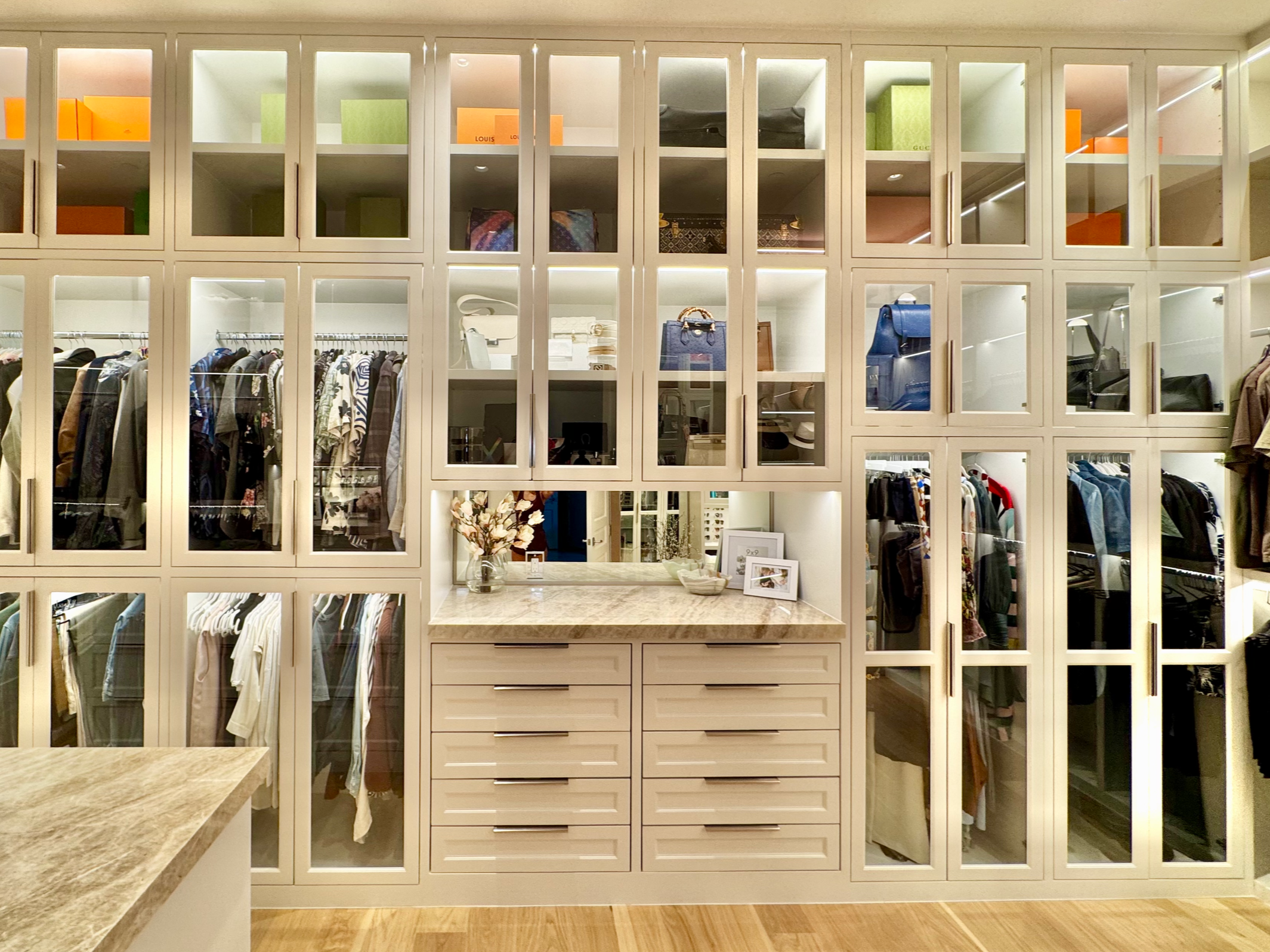 Organized walk in closet with organized clothes, organized handbags and accessories, and matching white velvet hangers — professional home organization services by Ordered Living Co. Austin TX