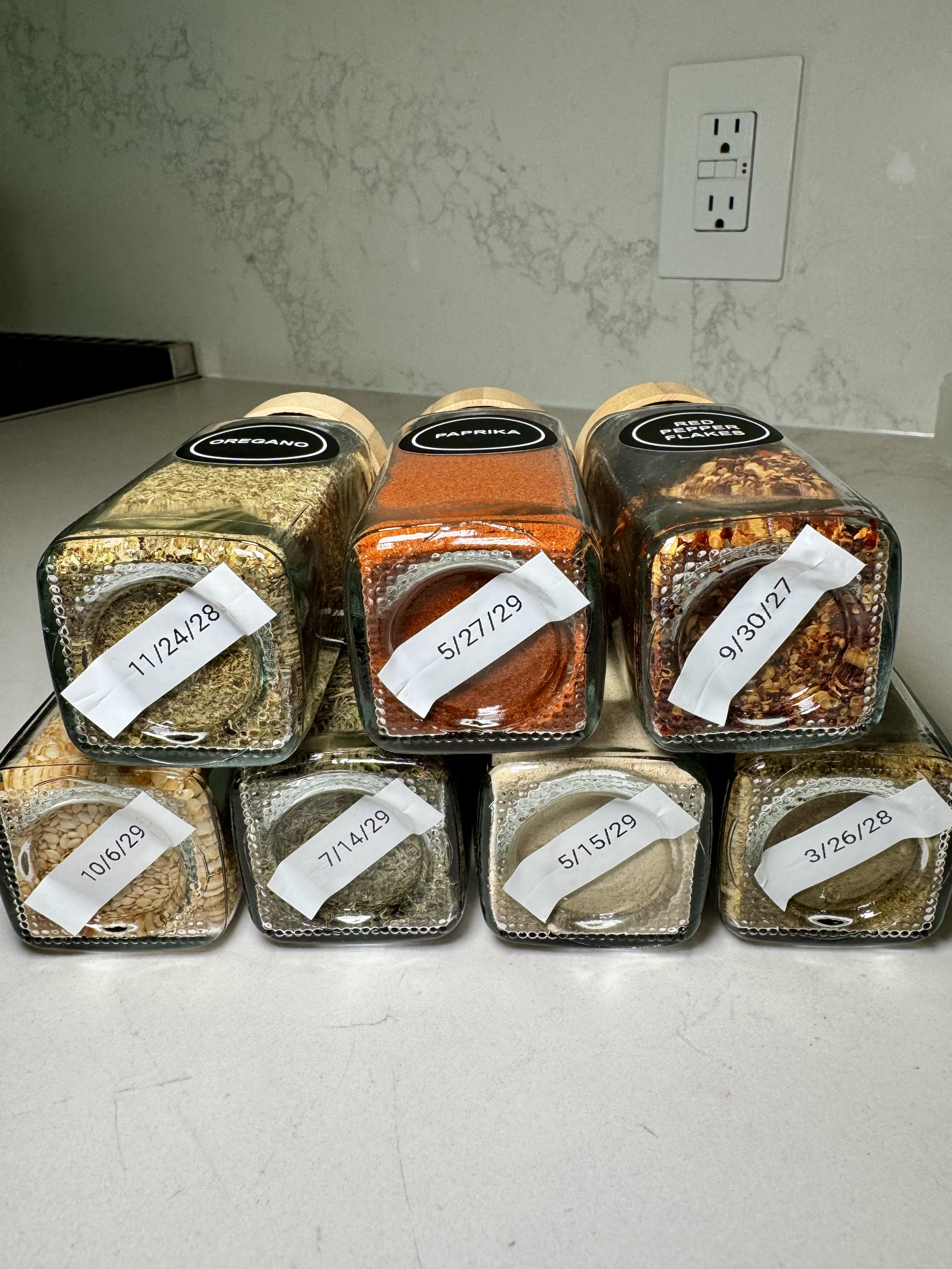 Glass spice jars filled with herbs and spices, labeled with dates and names - pantry organization, kitchen organization, spices organization, professional home organizing services in Austin TX by Ordered Living Co