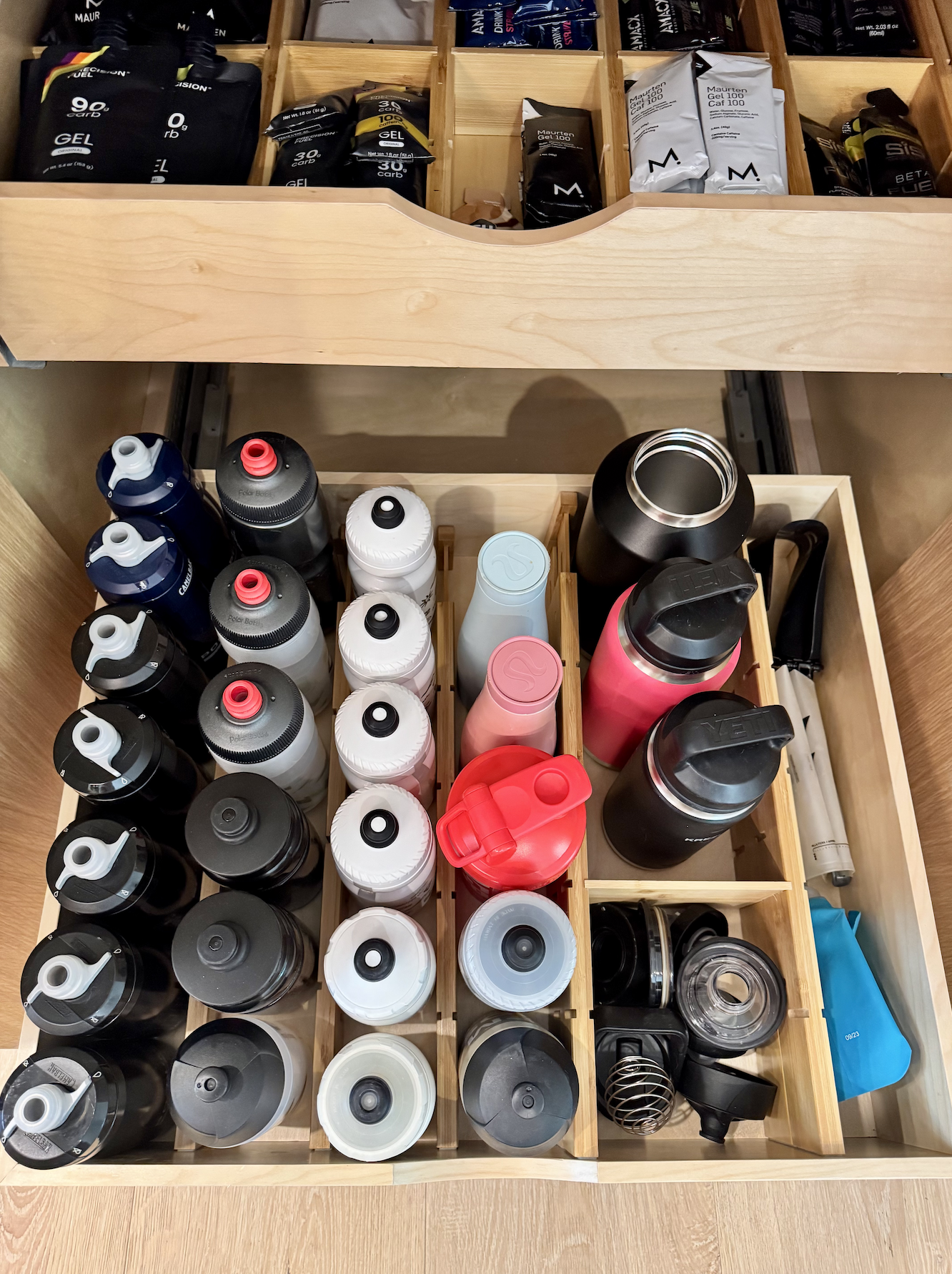 Organized kitchen drawer with bamboo dividers and categorized water bottles — professional kitchen organization by Ordered Living Co. Austin TX