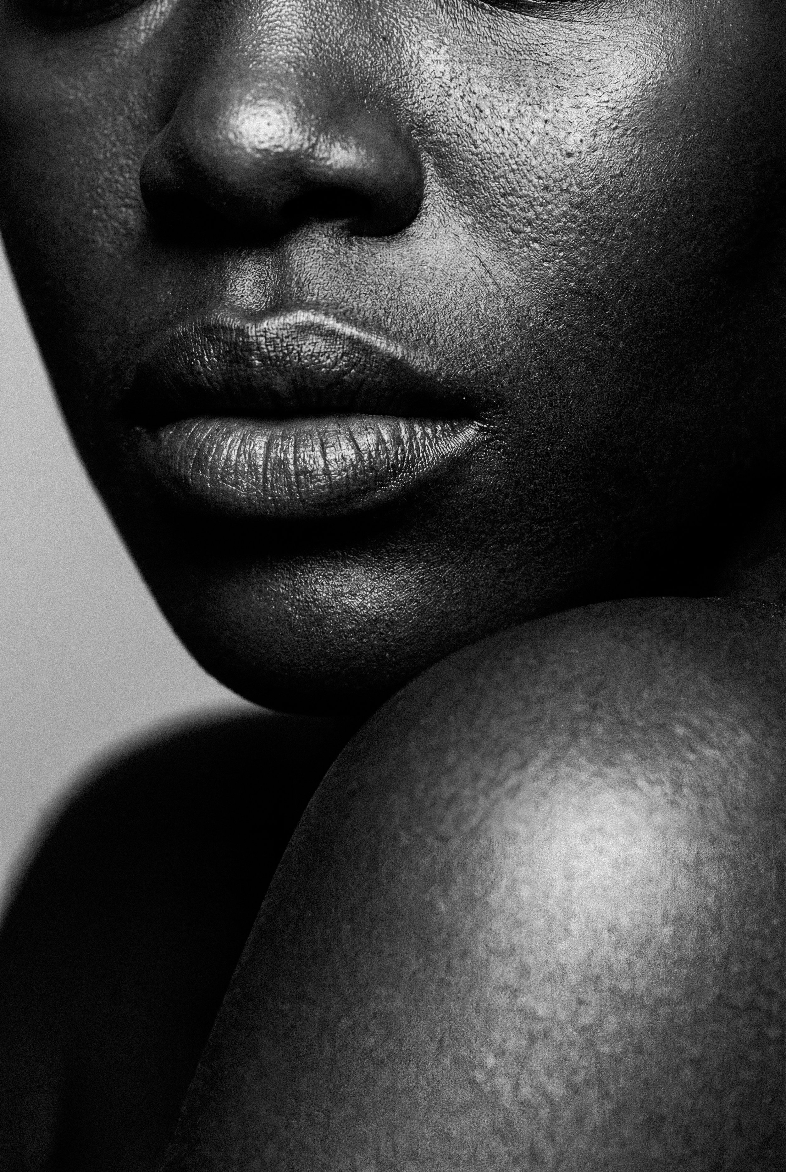 Close-up black and white photograph of a person's lips, nose, and skin texture.