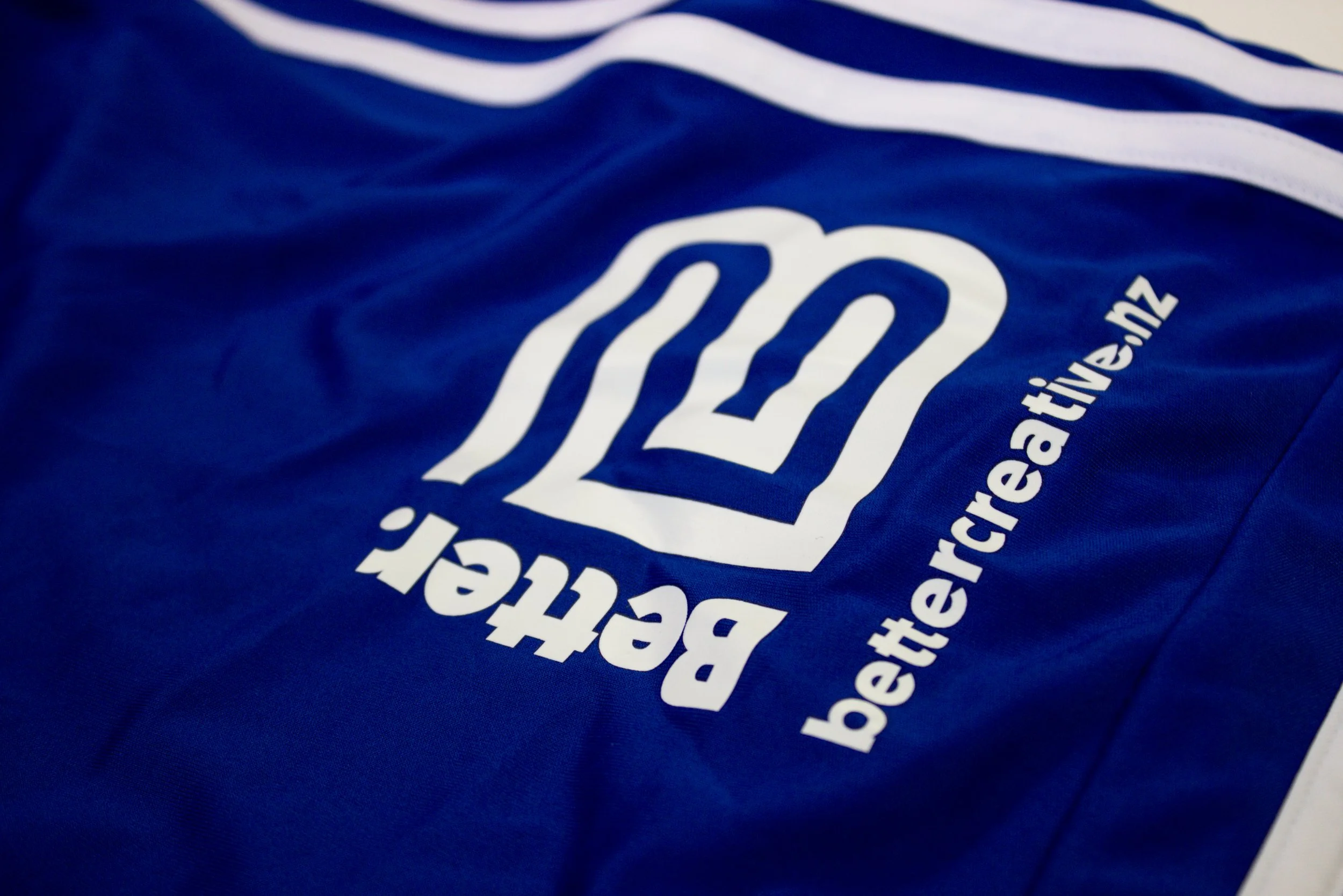 Close-up of a blue fabric bag with white text and a logo, including wavy lines and a website address.