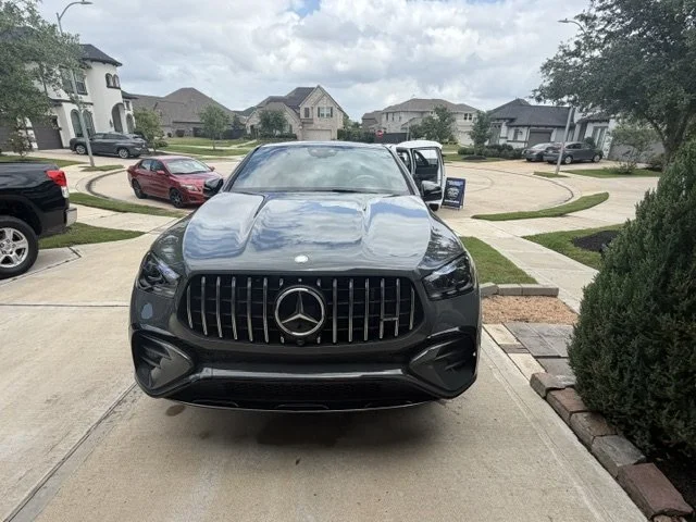 Black Mercedes-Benz SUV parked in a driveway in a suburban neighborhood.