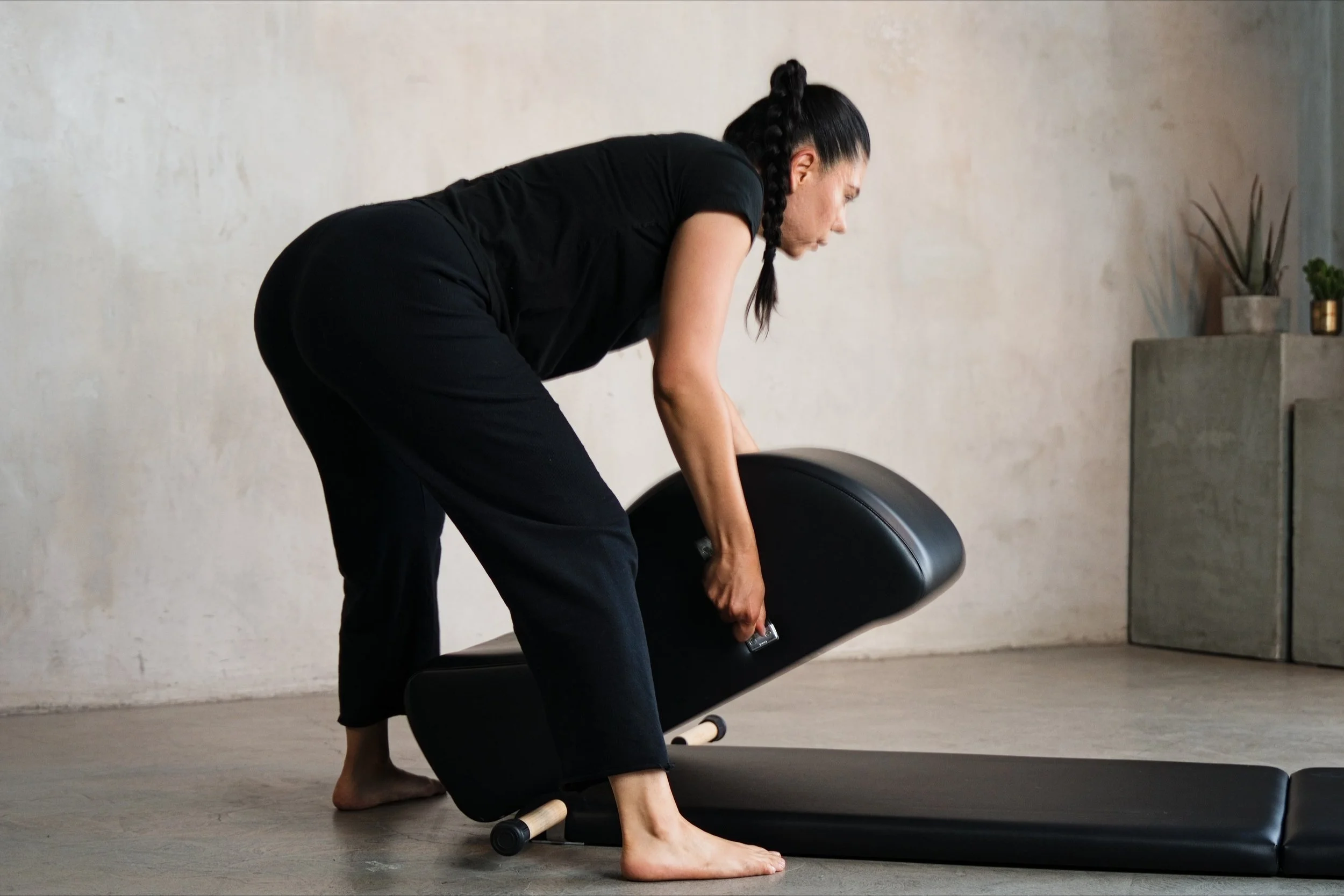 A woman setting up a Gratz Spine Corrector for classical Pilates.