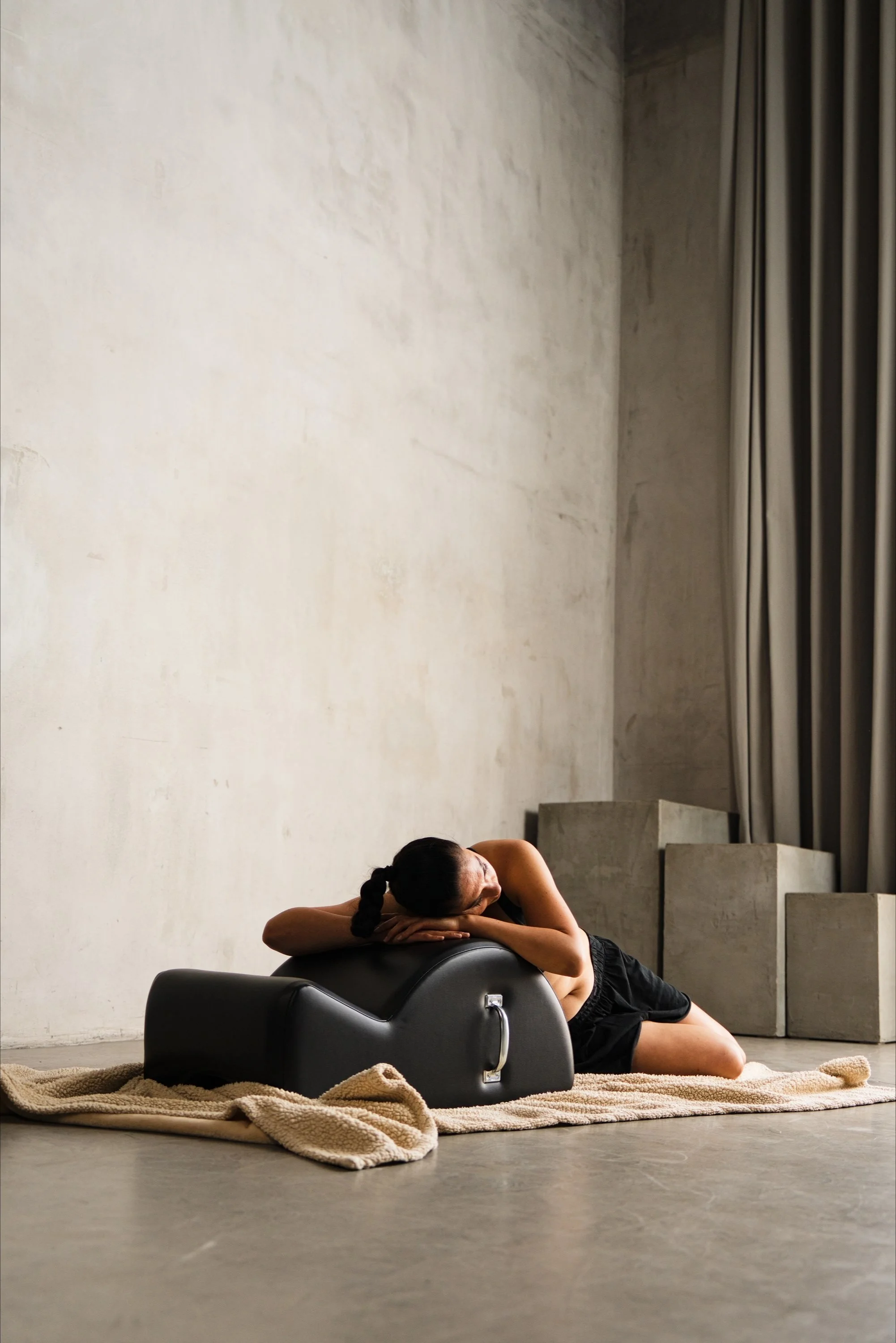 A woman lying on a Gratz Spine Corrector for Classical Pilates.