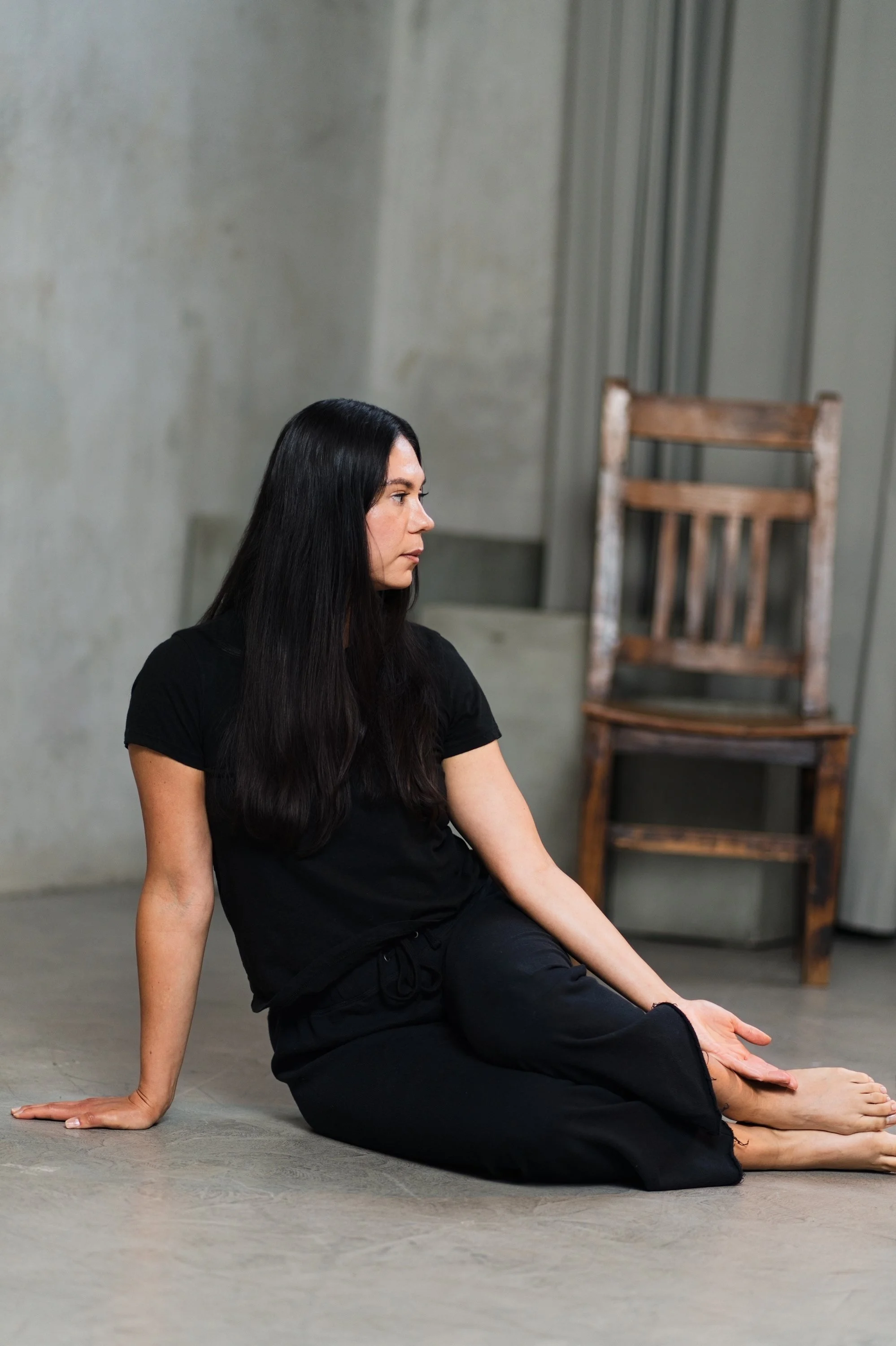 A woman sitting on the floor preparing for a Mermaid Side Bend.
