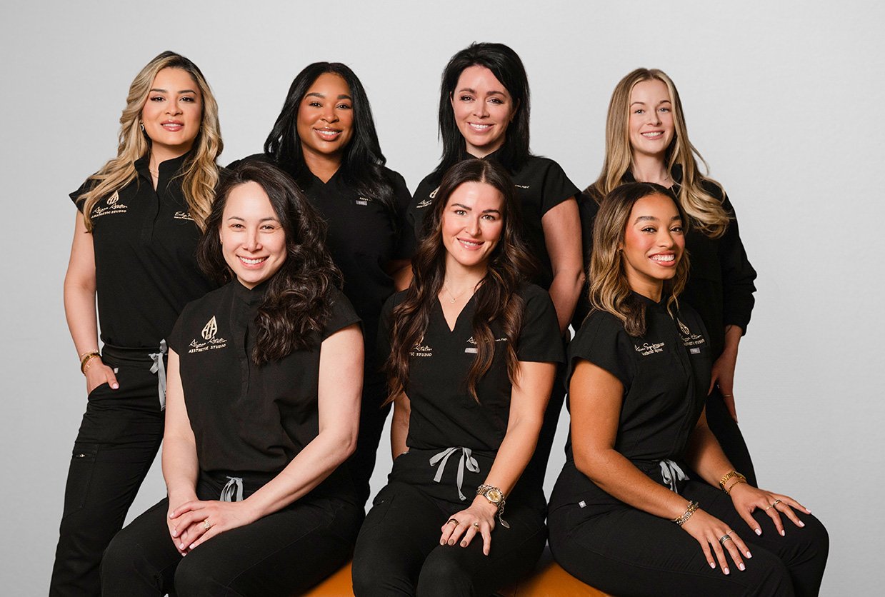 Group of eight women in black uniforms posing for a photo against a white background.