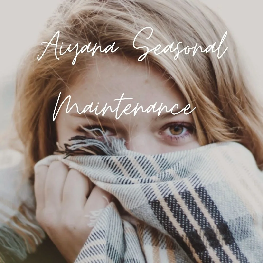 A person with reddish hair holding a plaid blanket over their mouth and nose, with one eye visible. Overlaid text reads 'Ayana Seasonal Maintenance.'