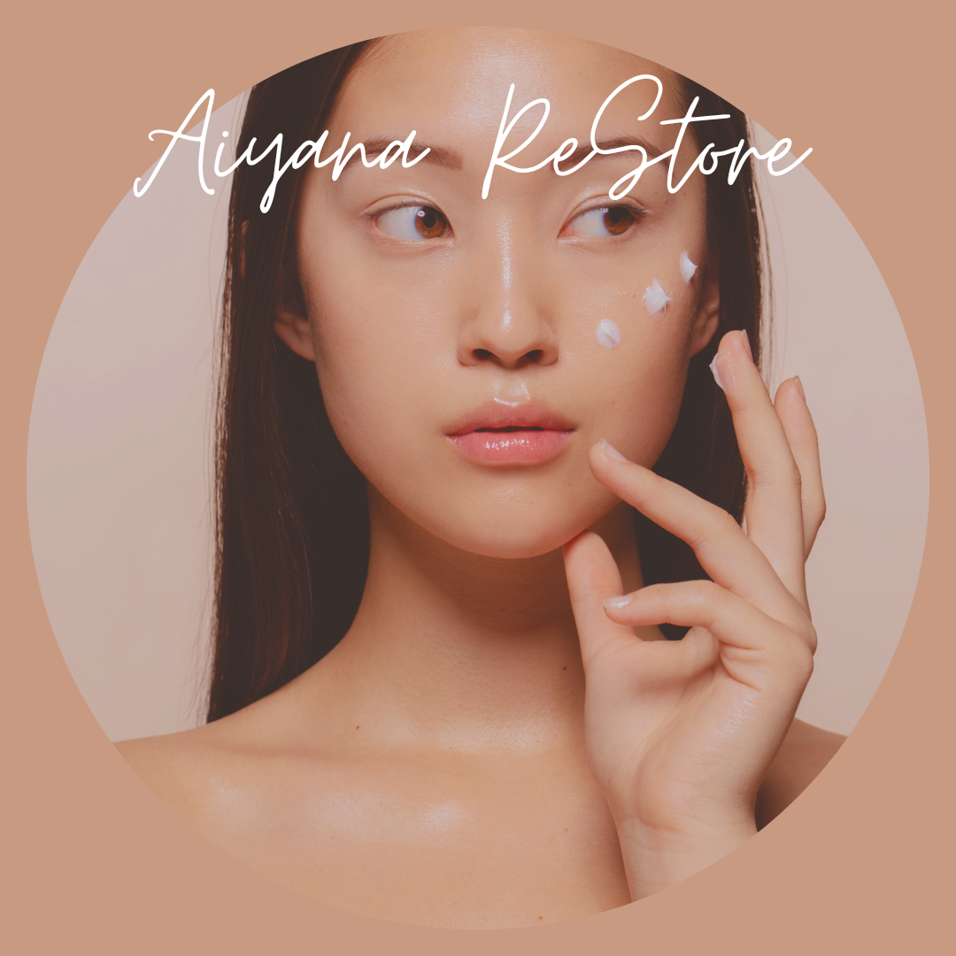A woman with clear skin applying skincare cream on her face, with the text 'Aiyanda Restore' over her face and a beige background.