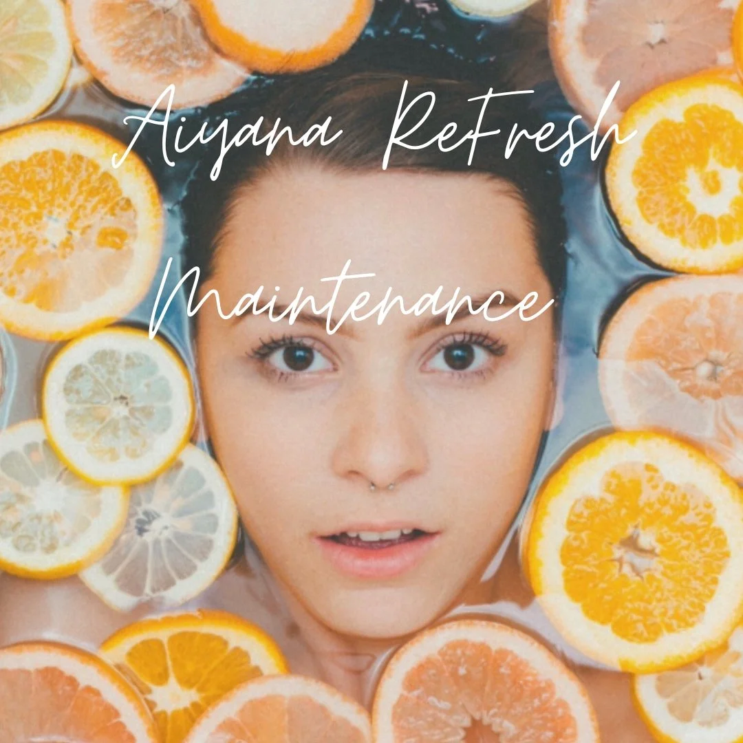 A woman with brown hair and blue eyes lying in water surrounded by slices of lemon, orange, and grapefruit.