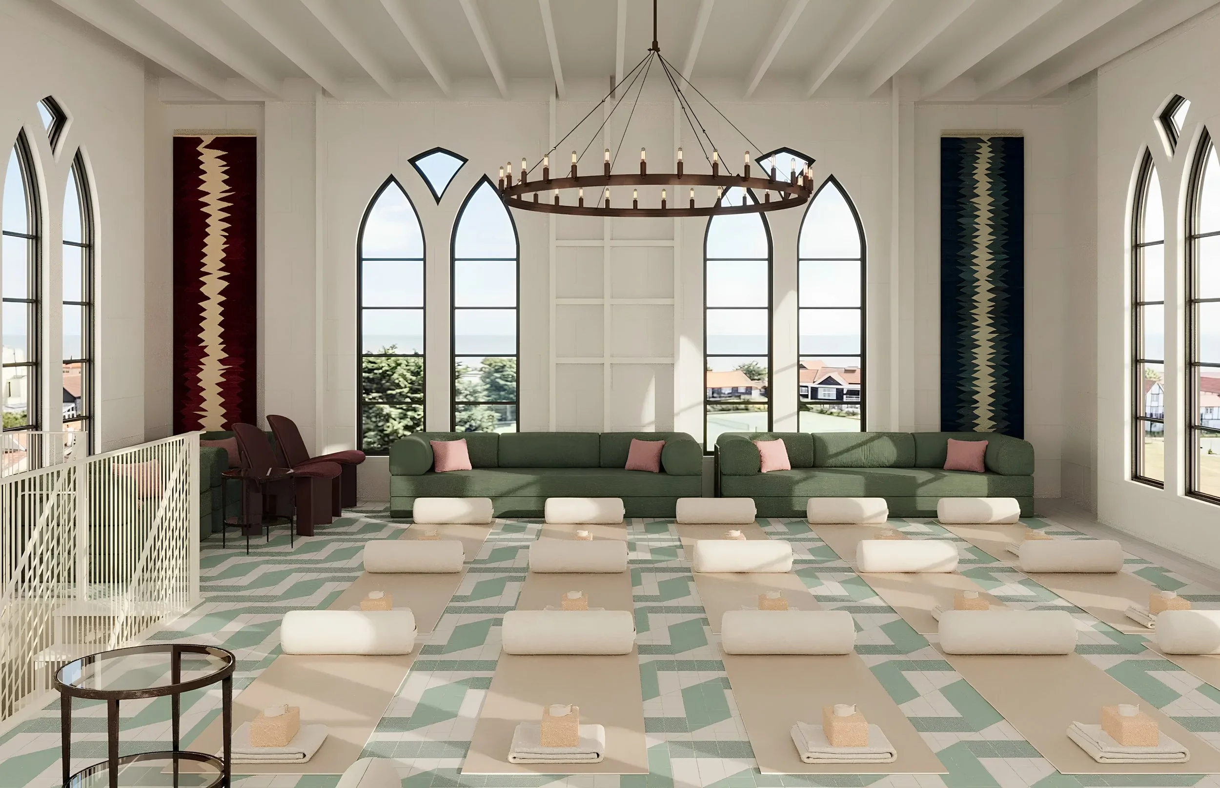 Interior of a modern room with large arched windows, a circular chandelier, green couches with pink pillows, and a patterned floor. Construction materials are visible on the floor.
