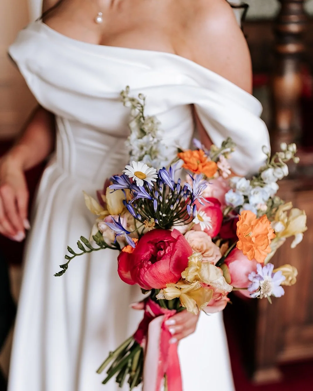A woman in a white dress holding a colorful bouquet of flowers.