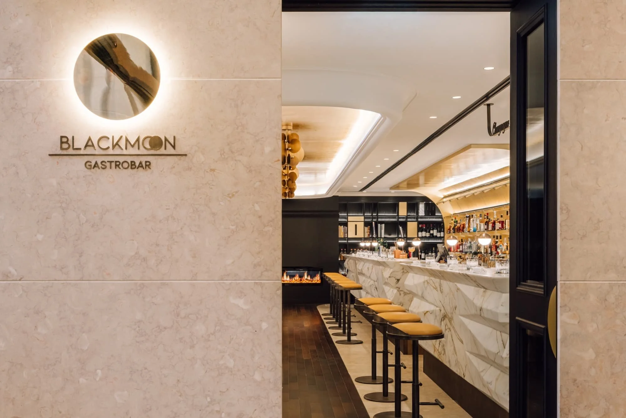 Entrance to Blackmon Gastobar with bar seats and marble counter inside a modern restaurant.