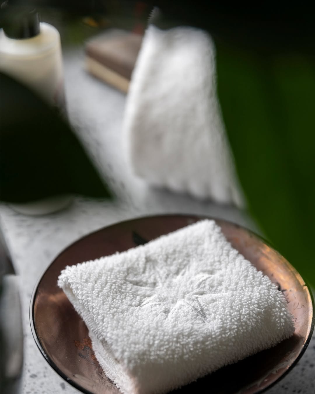 A white, textured cloth napkin on a copper plate with star-shaped details.