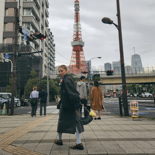People crossing a busy street with Tokyo Tower in the background, in an urban cityscape.