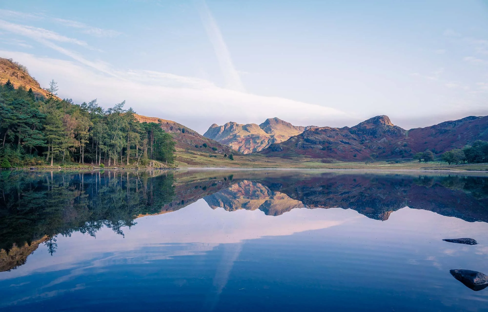 Scenic view of a mountain range reflected in a calm lake, with a partly cloudy sky above.