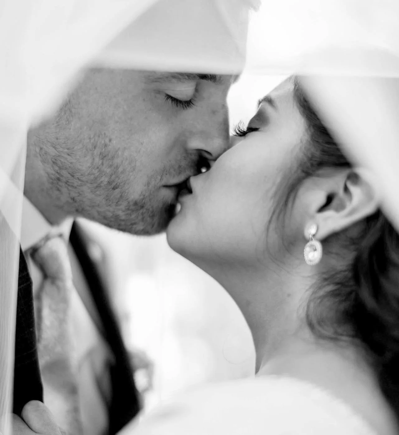 Black and white close-up of a couple about to kiss, with their eyes closed and faces touching.