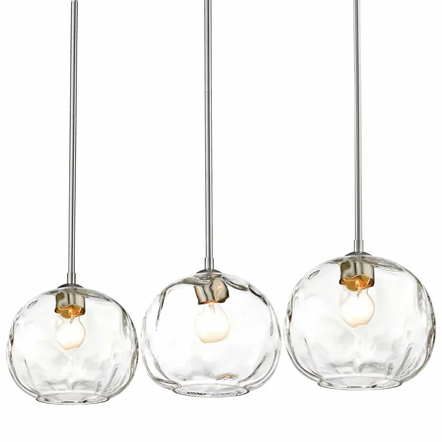 Three modern pendant lights with clear glass globes and exposed bulbs hanging in a row.