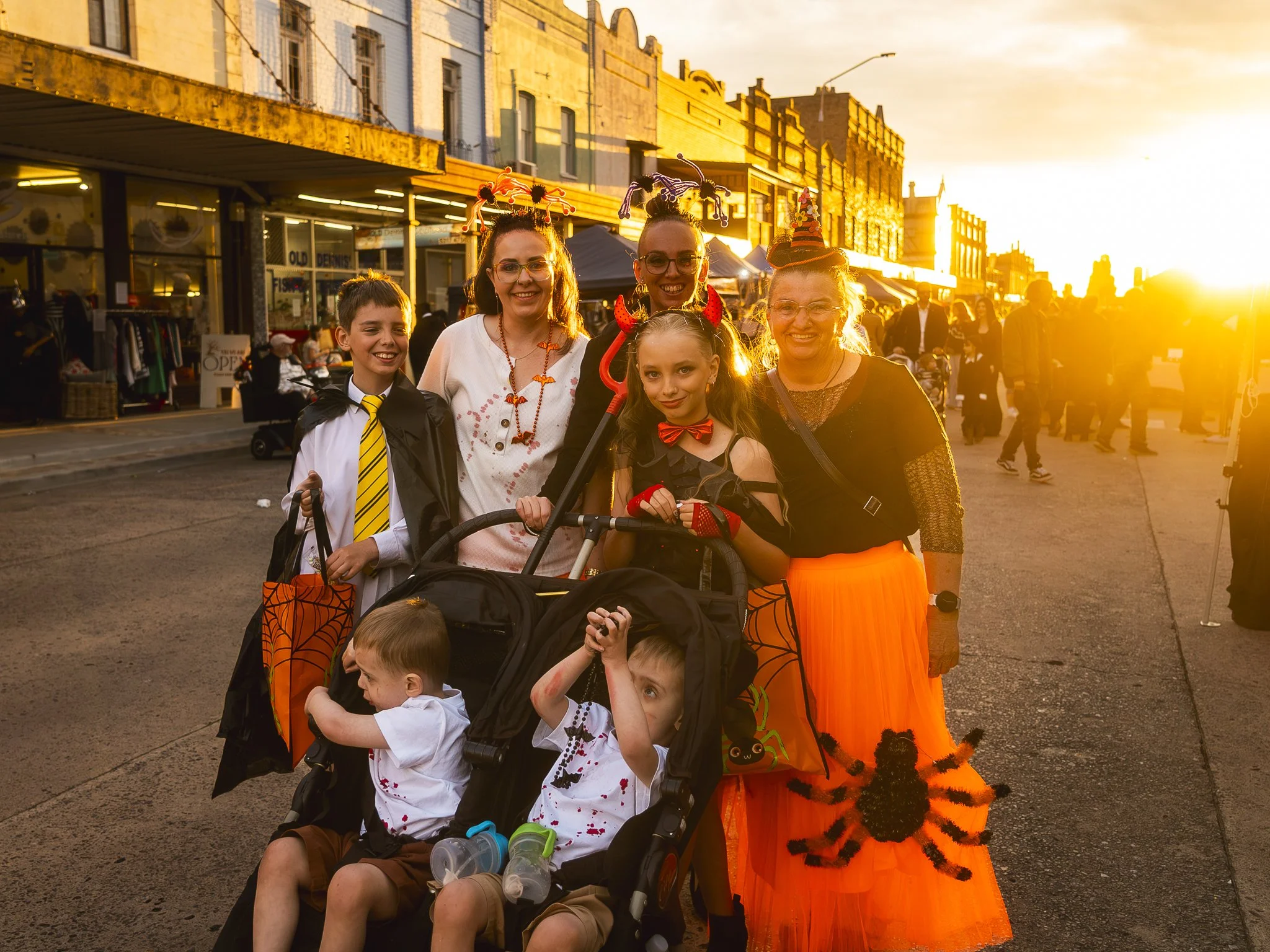 Group of people dressed in Halloween costumes standing outdoors during sunset.