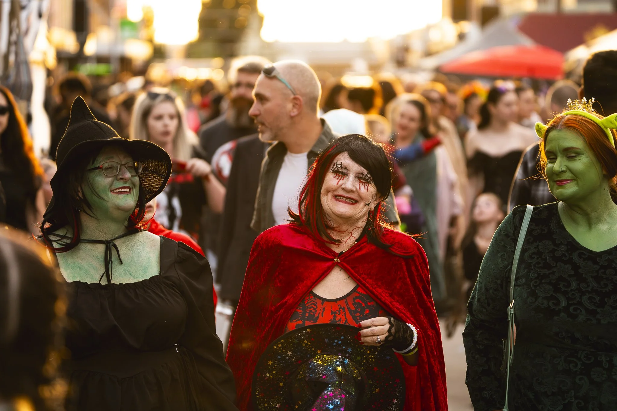 People dressed in Halloween costumes at a festive outdoor event in the evening.