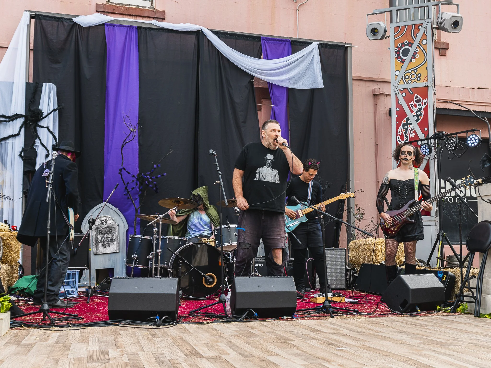 Live band performing on stage with Halloween-themed decorations, including a spider decoration and tombstone prop.