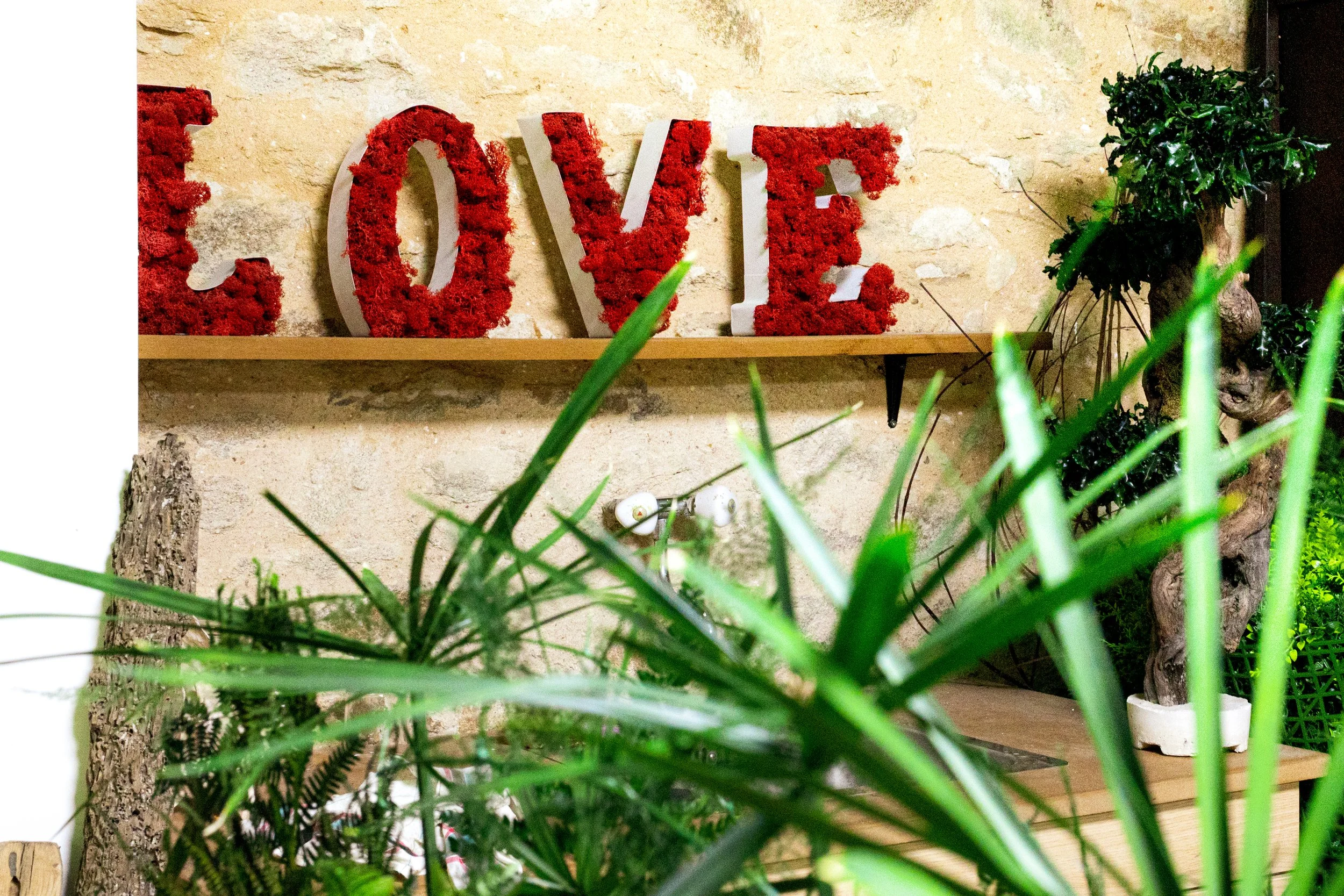 Les lettres 'LOVE' décoratives rouges et blanches sur une étagère en bois, décorées de fleurs rouges.
