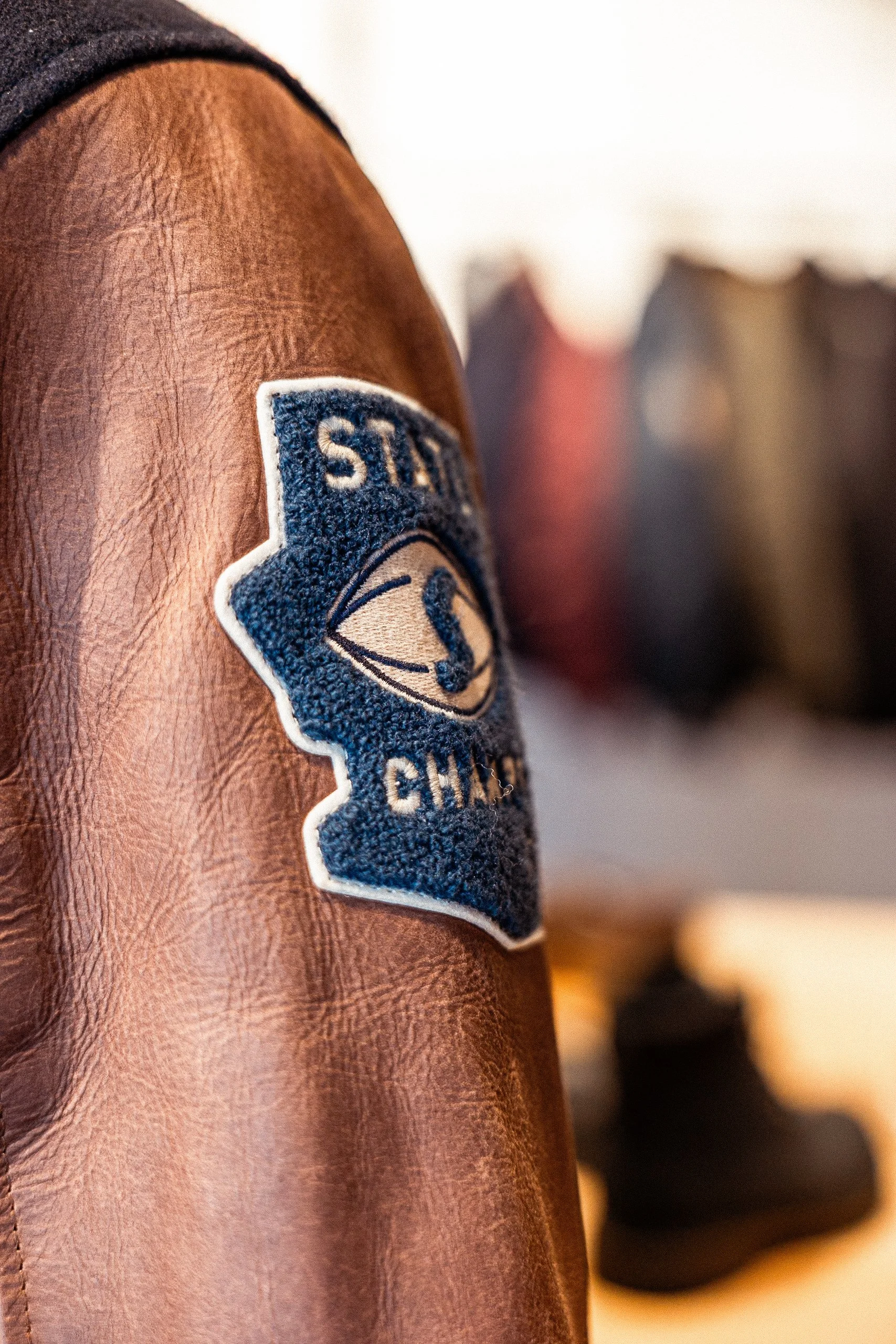 Gros plan d'une épaulette de veste en cuir avec un patch en tissu brodé avec le logo d'une équipe de hockey.