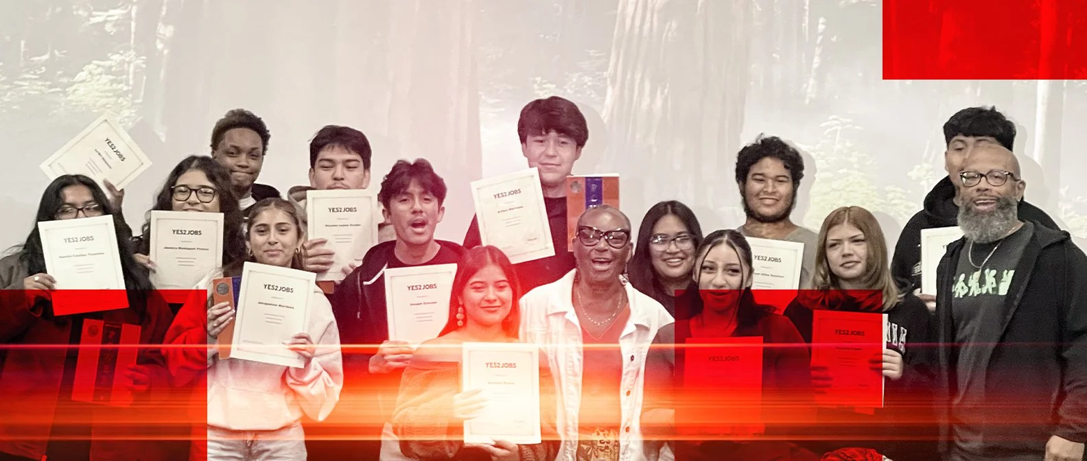 Group of young adults and an older woman, some holding certificates, standing outdoors in front of trees, celebrating an achievement.