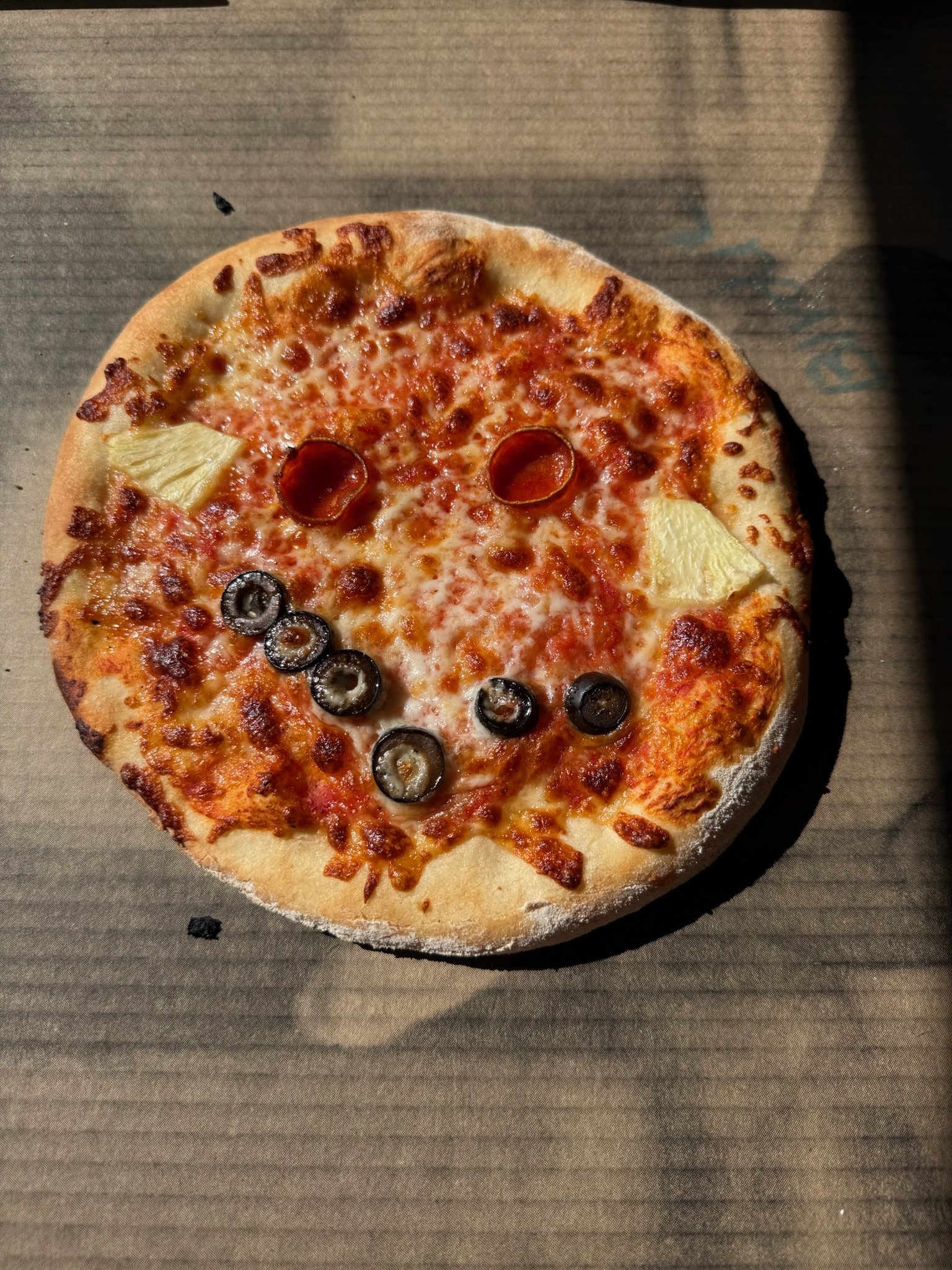 A pepperoni and black olive pizza on a cardboard surface.