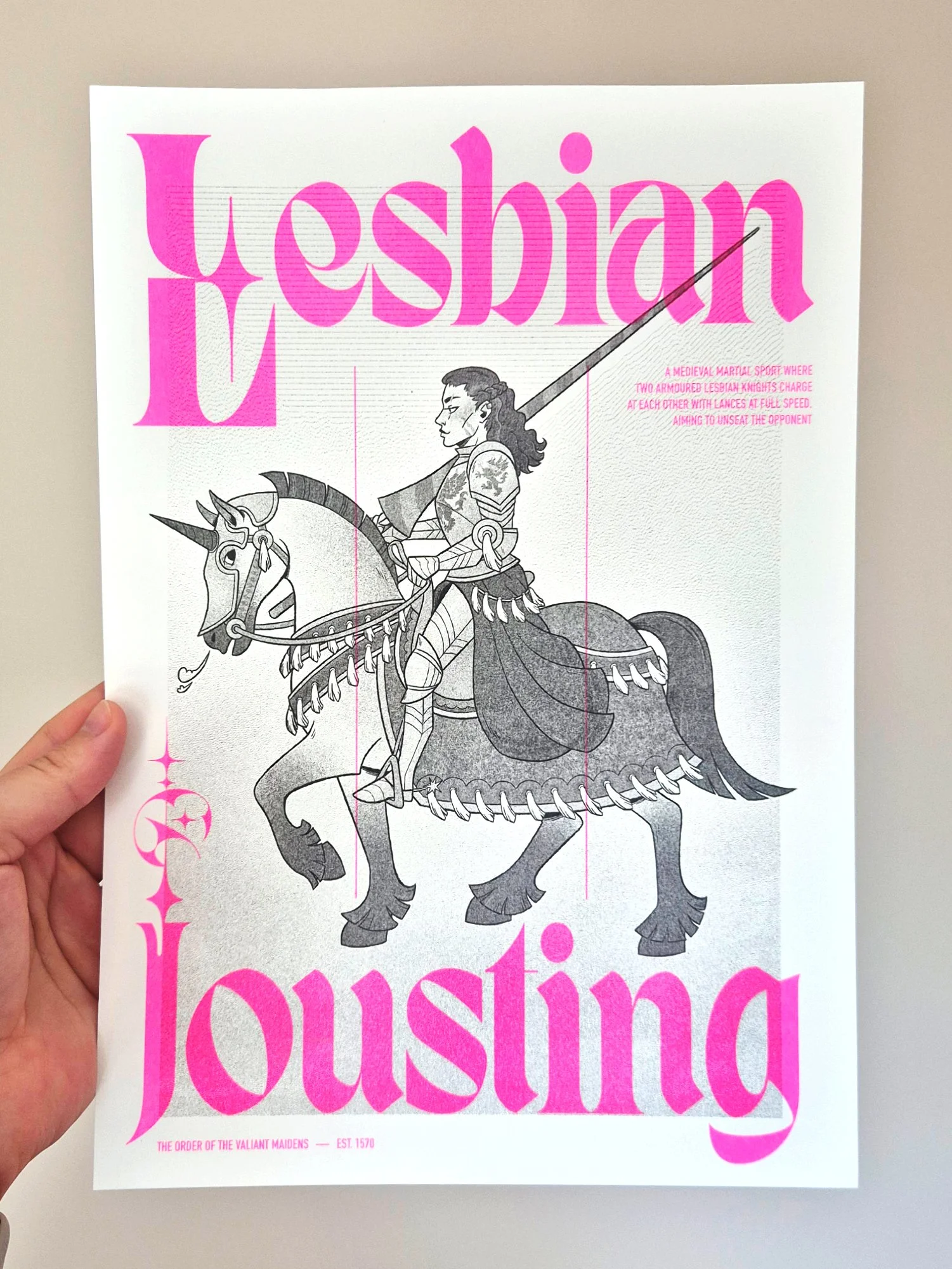 A photo of a risograph print showing a female knight sitting on a horse and holding a long lance. The character is in greyscale and there's a fluo pink gothic type overlaid on top.