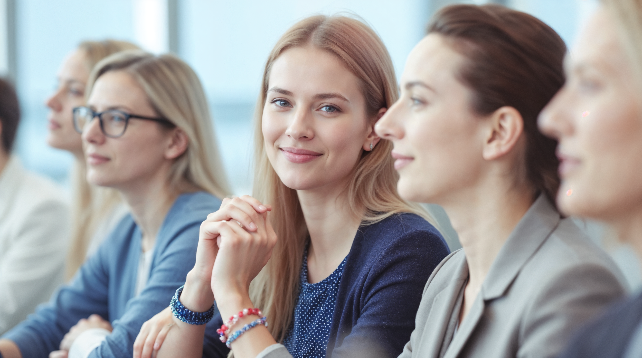Menschen in einer Konferenz oder Besprechung, sitzend in einer Reihe, freundlich und aufmerksam, im professionellen Umfeld.