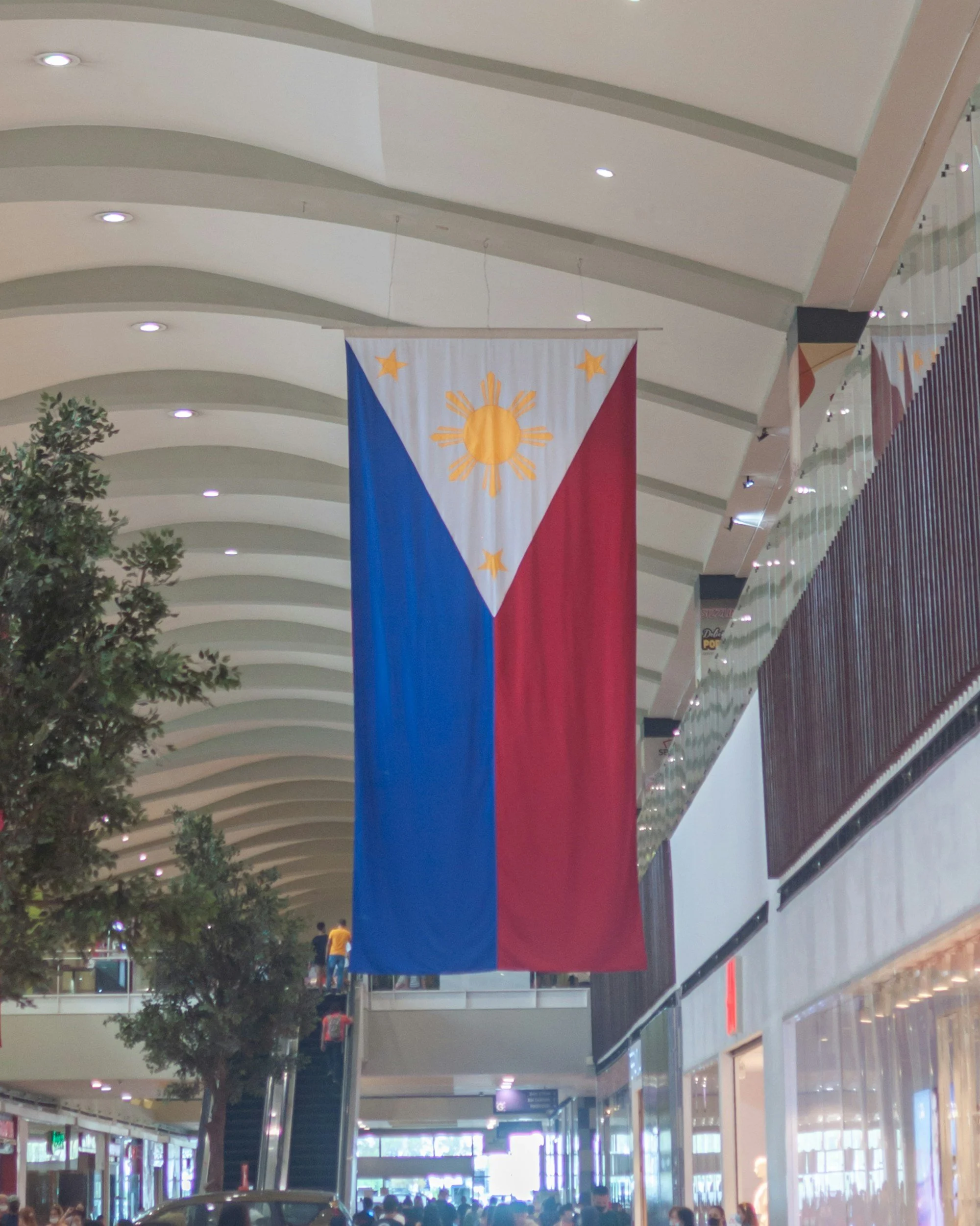 Large Philippine flag hanging inside a modern shopping mall.