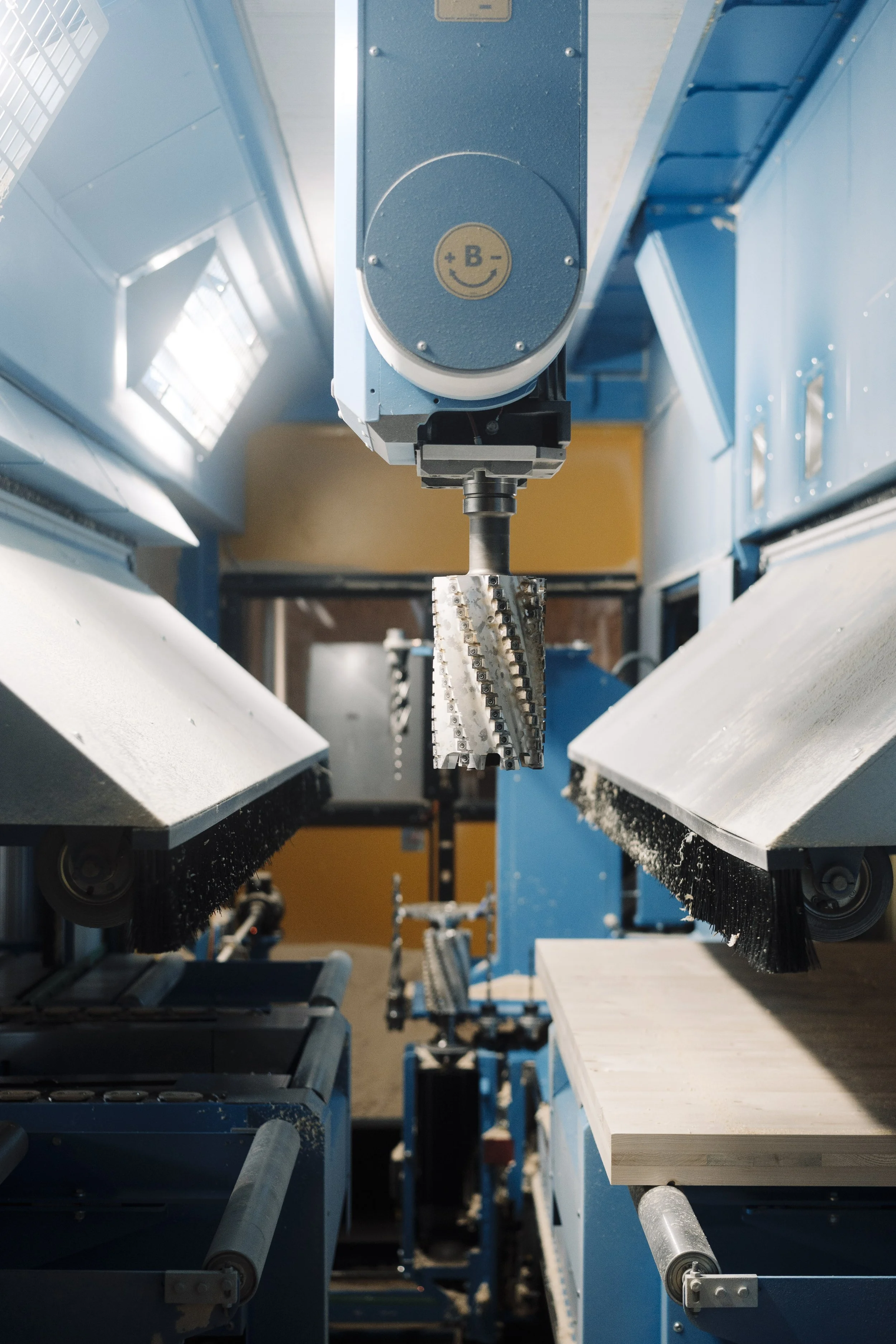Industrielle Maschine mit Förderbändern und mechanischen Greifern in einer Fabrikhalle.