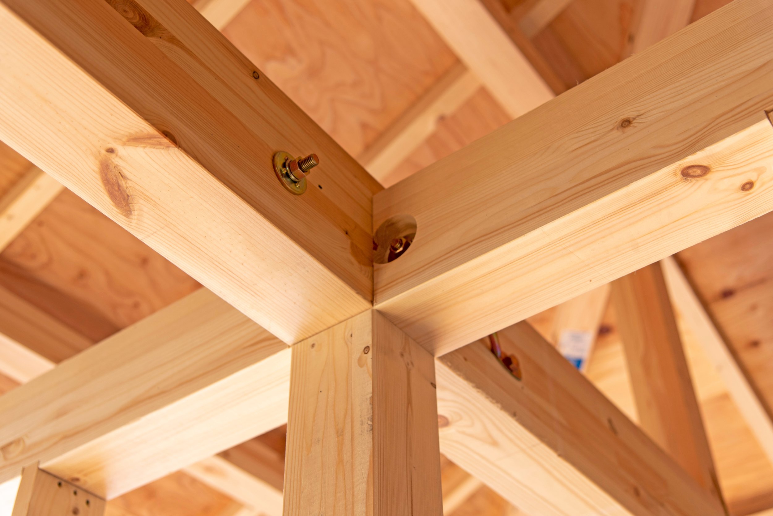Holzrahmen für ein Gebäude unter Konstruktion, sichtbare Verbindungselemente und Holzträger.