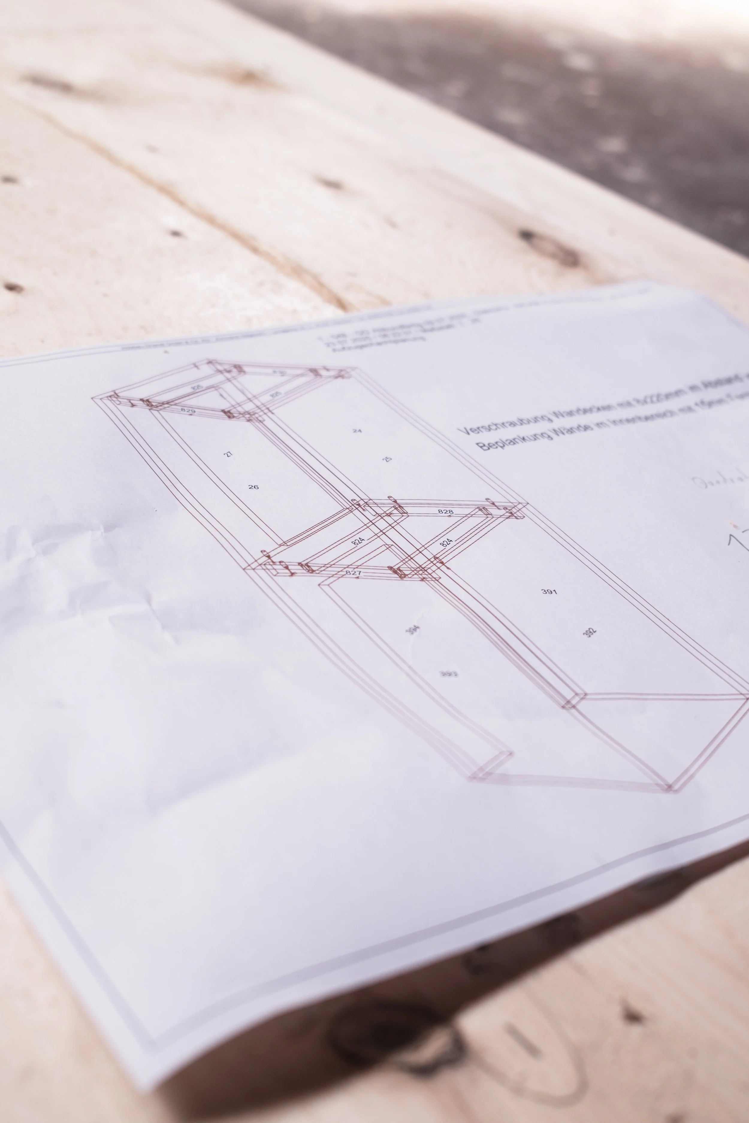Technischer Bauplan auf einem weißen Papier liegt auf einem Holzschnitt.