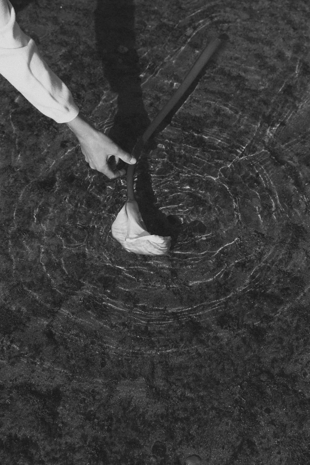 A person using a machete to cut a bag of trash on a dark, textured surface.