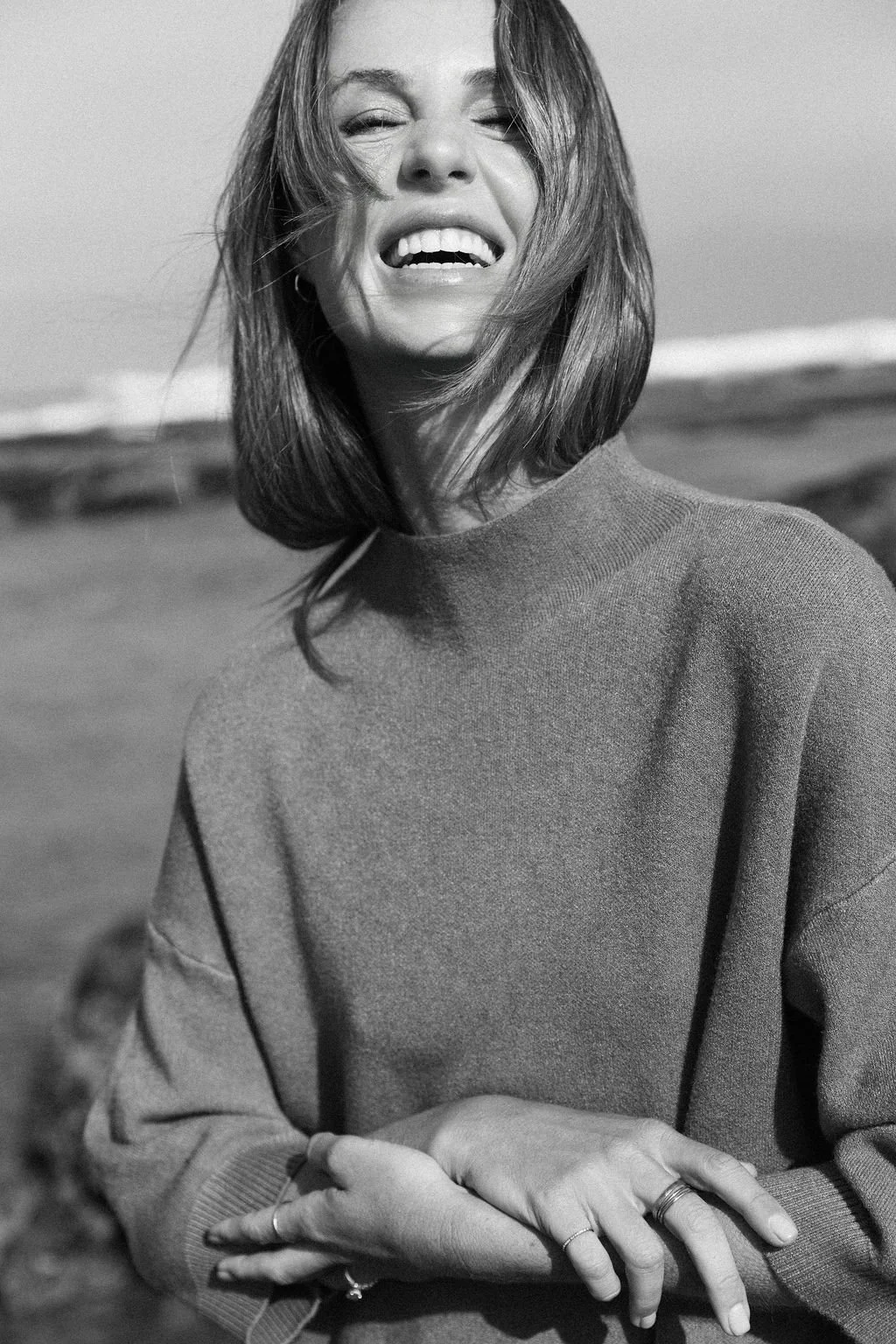Keiarna from Gentle Currents with shoulder-length hair smiling and squinting in a black-and-white photo, wearing a sweater outdoors.